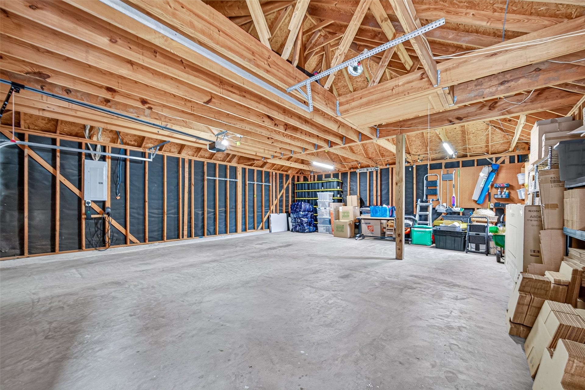 Spacious garage with high ceilings, exposed beams, and ample storage space, perfect for vehicles, tools, or a workshop.