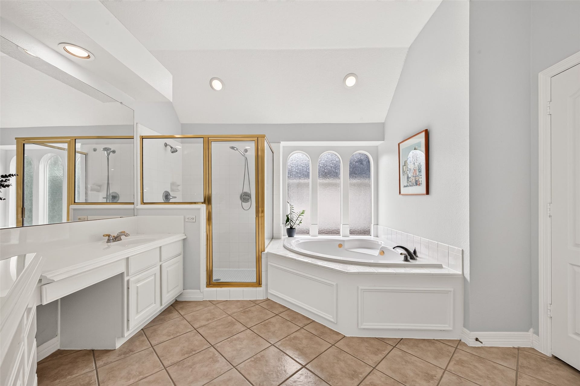 Primary bathroom featuring a spa like corner bathtub with a view, a separate glass enclosed shower and tile flooring.