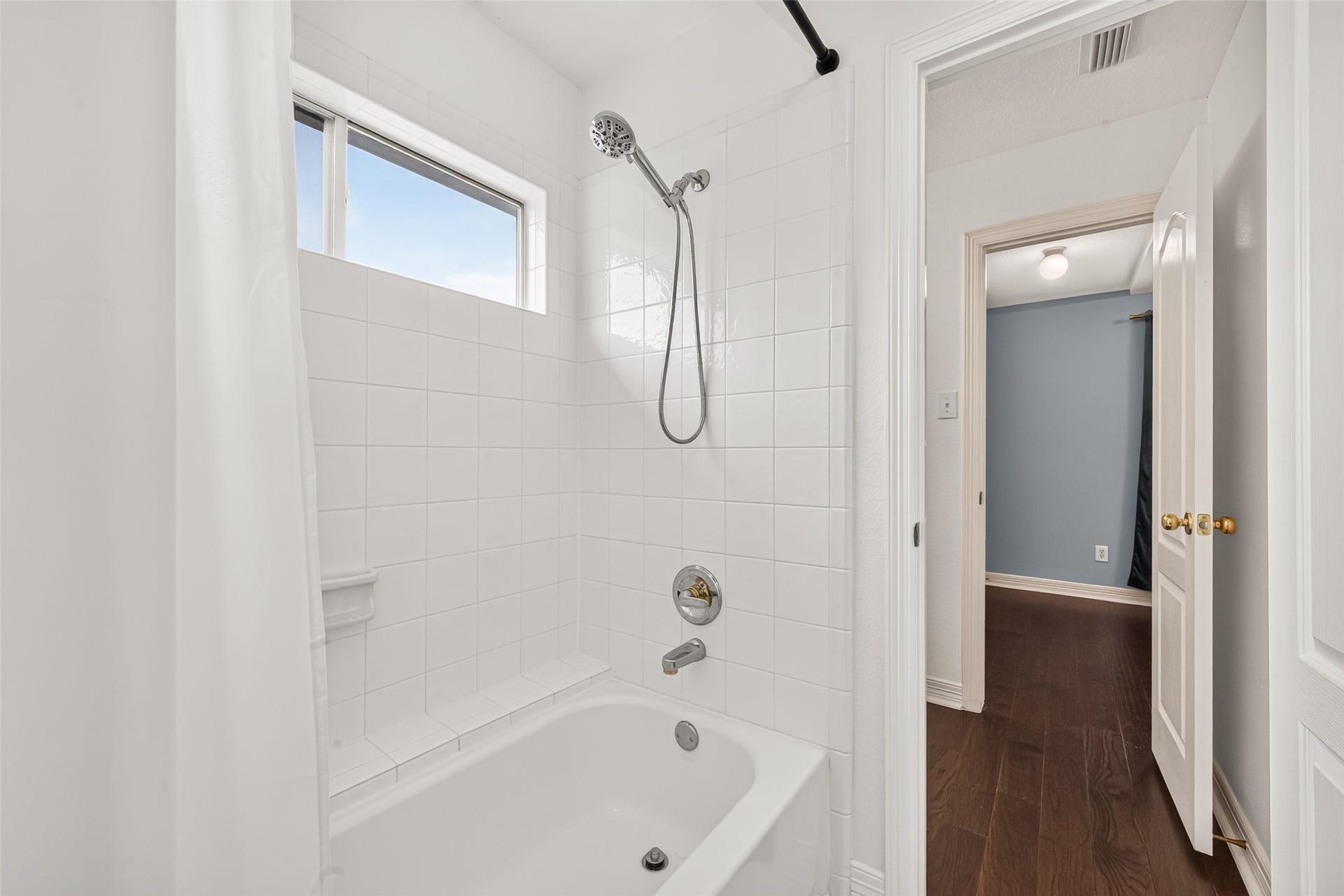 Jack and Jill bathroom with a classic white tiled shower, and a window for natural light.