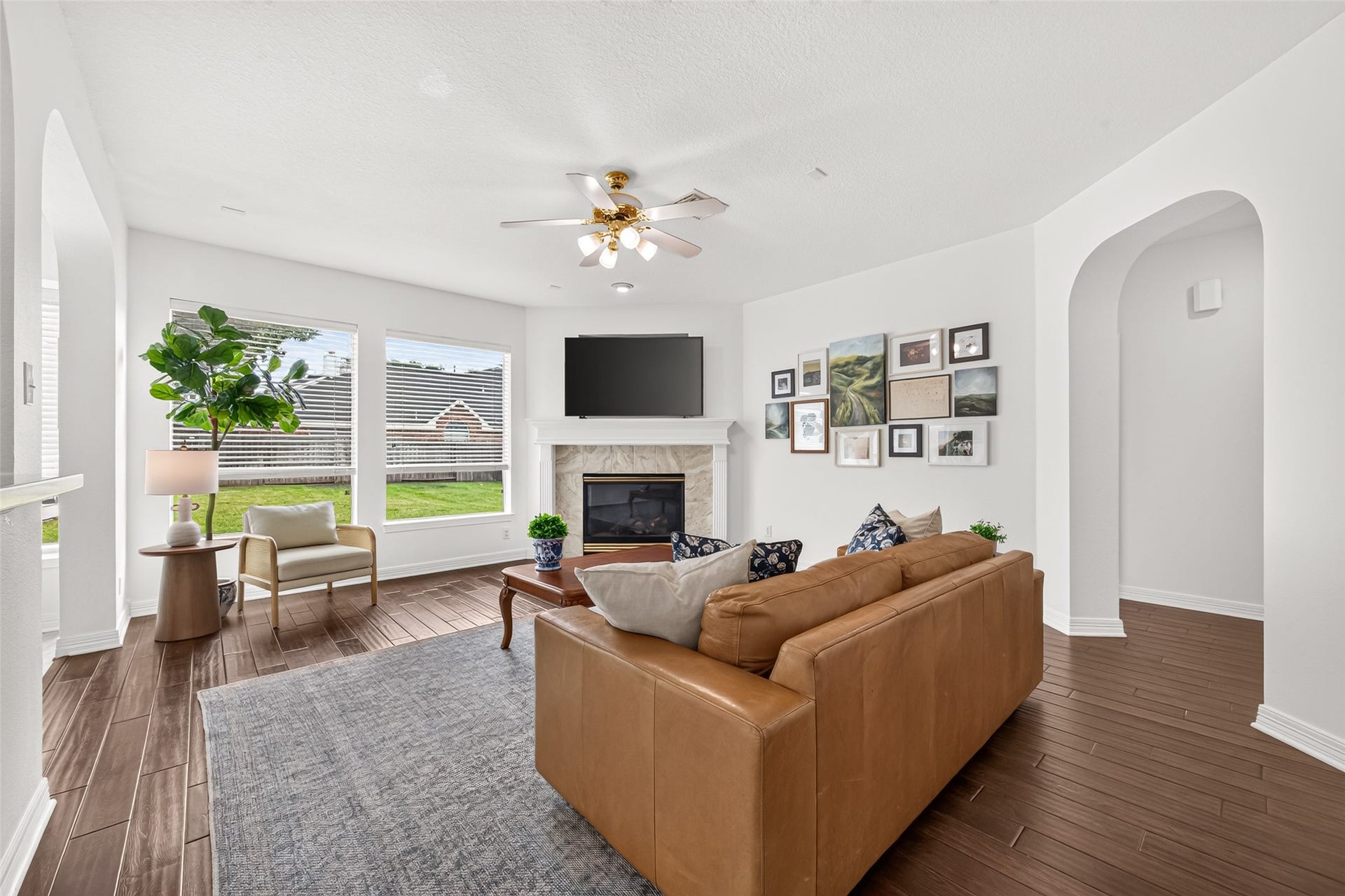 Spacious living area with hardwood floors, cozy fireplace, and large windows offering abundant natural light. light,