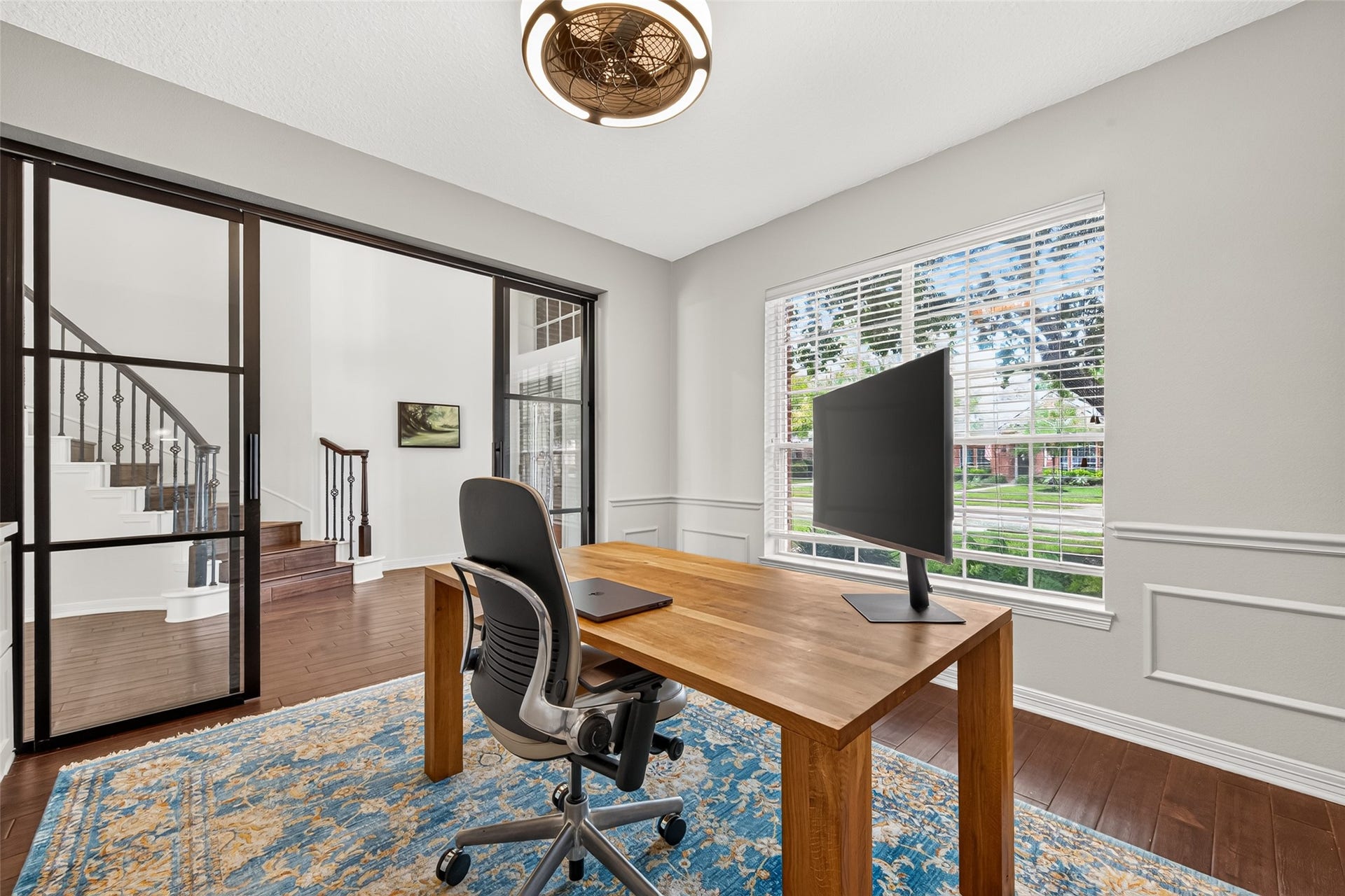 Private study featuring natural lighting, elegant glass doors, and rich wood flooring, offering a perfect workspace with a view.