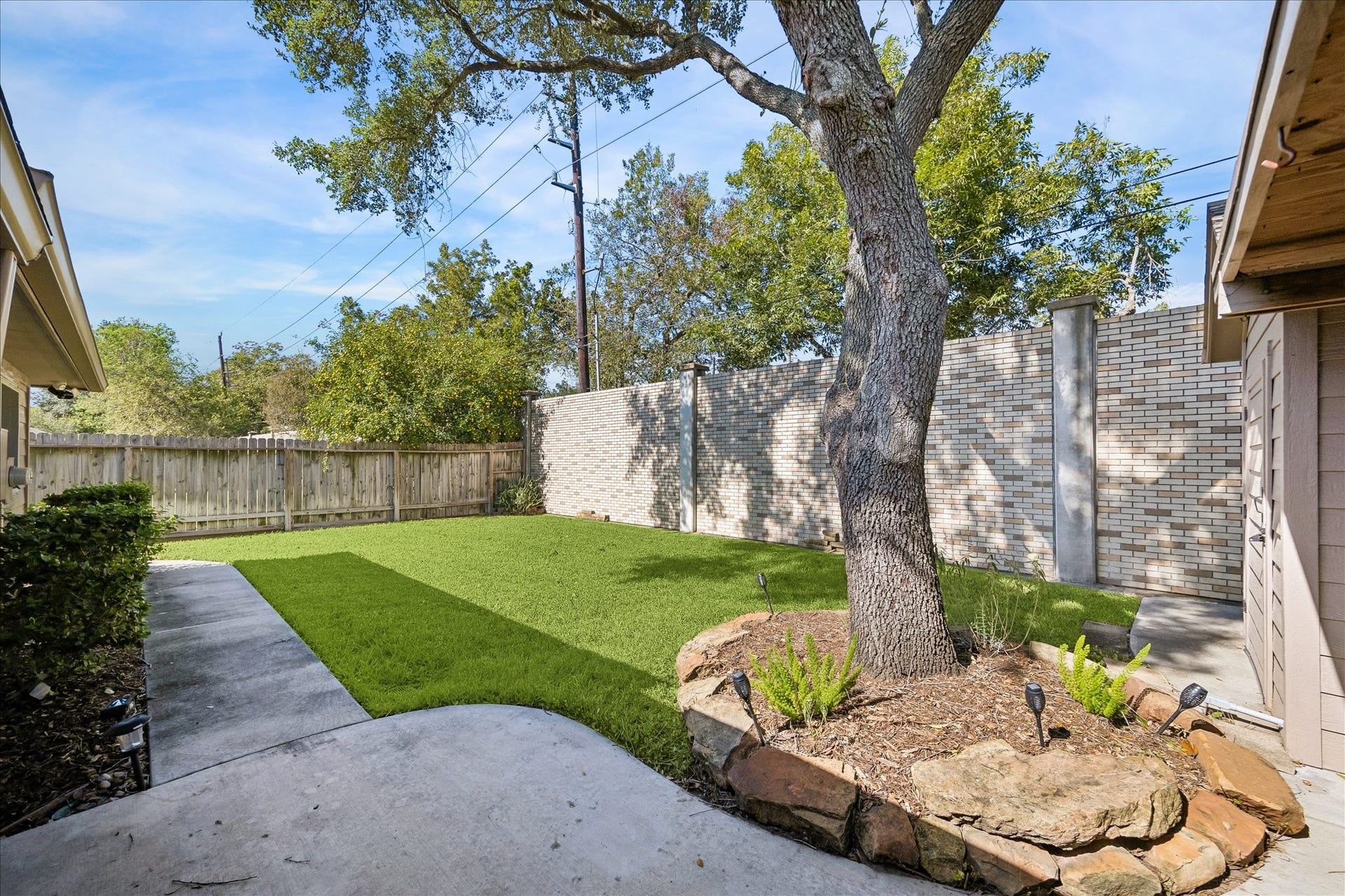 3911 Kitchen Hill Lane, Sugar Land, TX 77479 Enjoy your own fenced backyard with a grassy lawn, mature shade tree, and a charming stone-edged garden area.