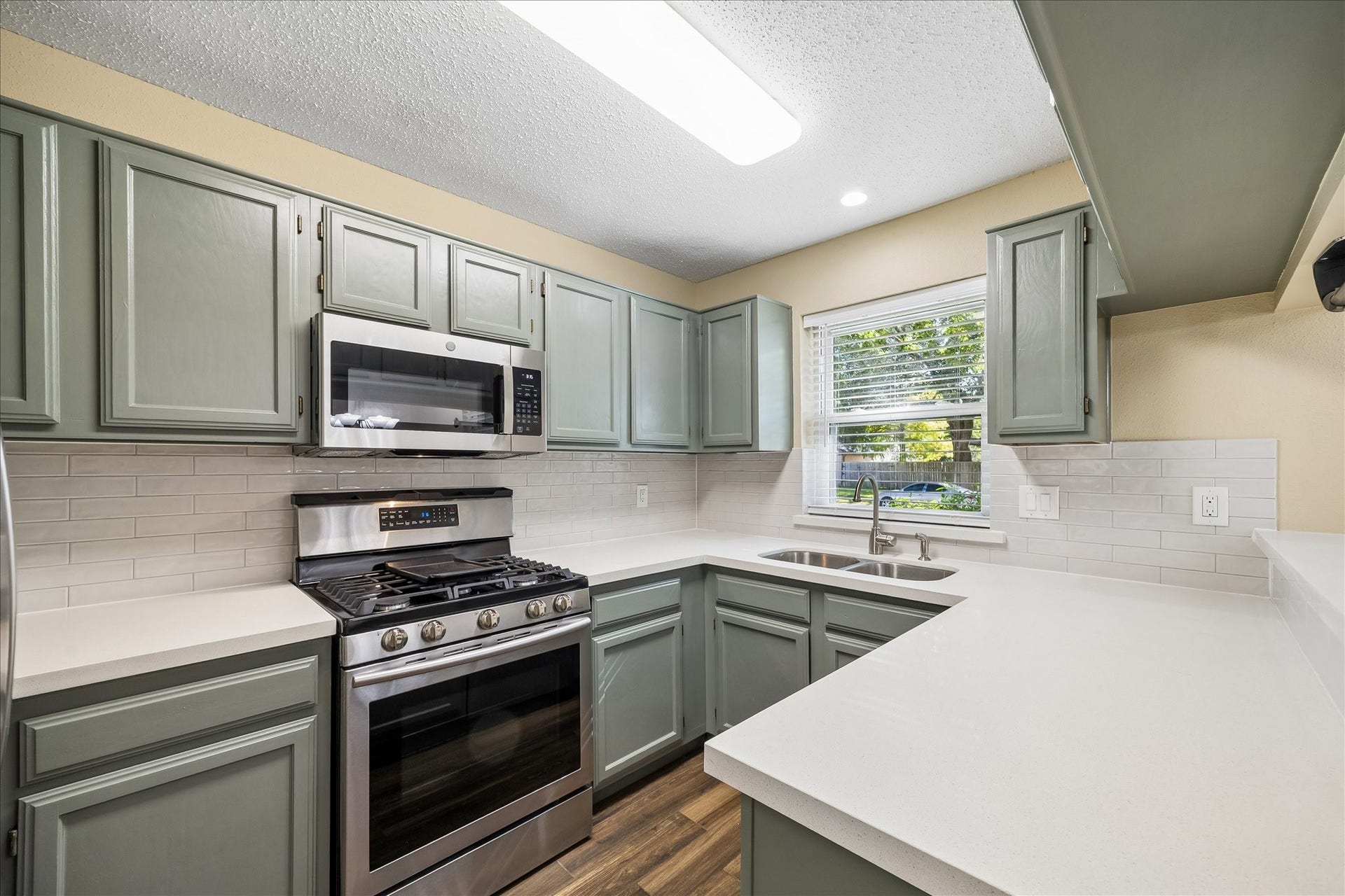 3911 Kitchen Hill Lane, Sugar Land, TX 77479 A kitchen you'll love coming home to! Enjoy attractive sage-green cabinetry, crisp white countertops, subway tile, and stainless steel appliances.
