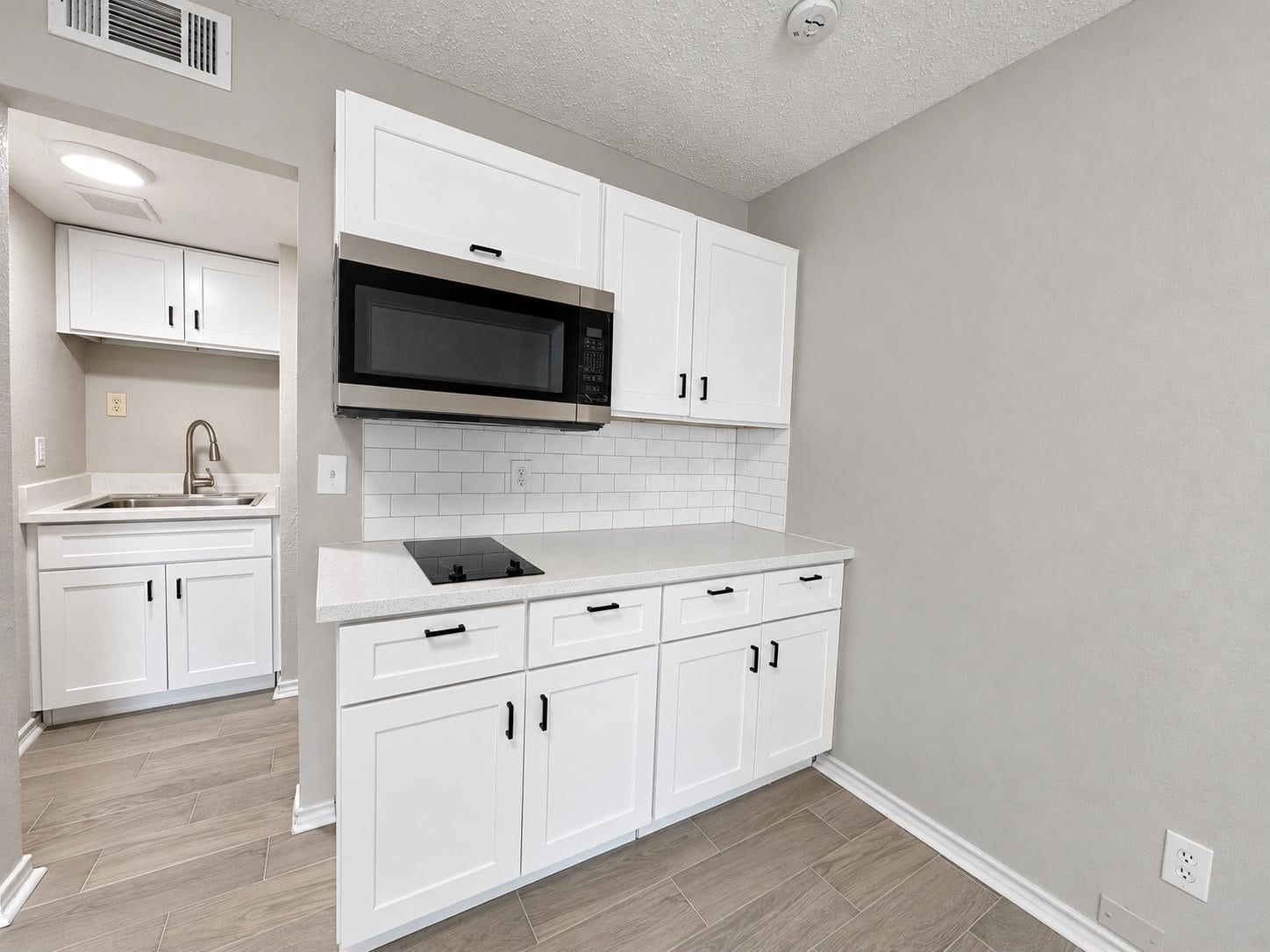 9711 Linkmeadow Lane, #12B, Houston, TX 77025 Modern kitchenette with white cabinetry and black hardware.