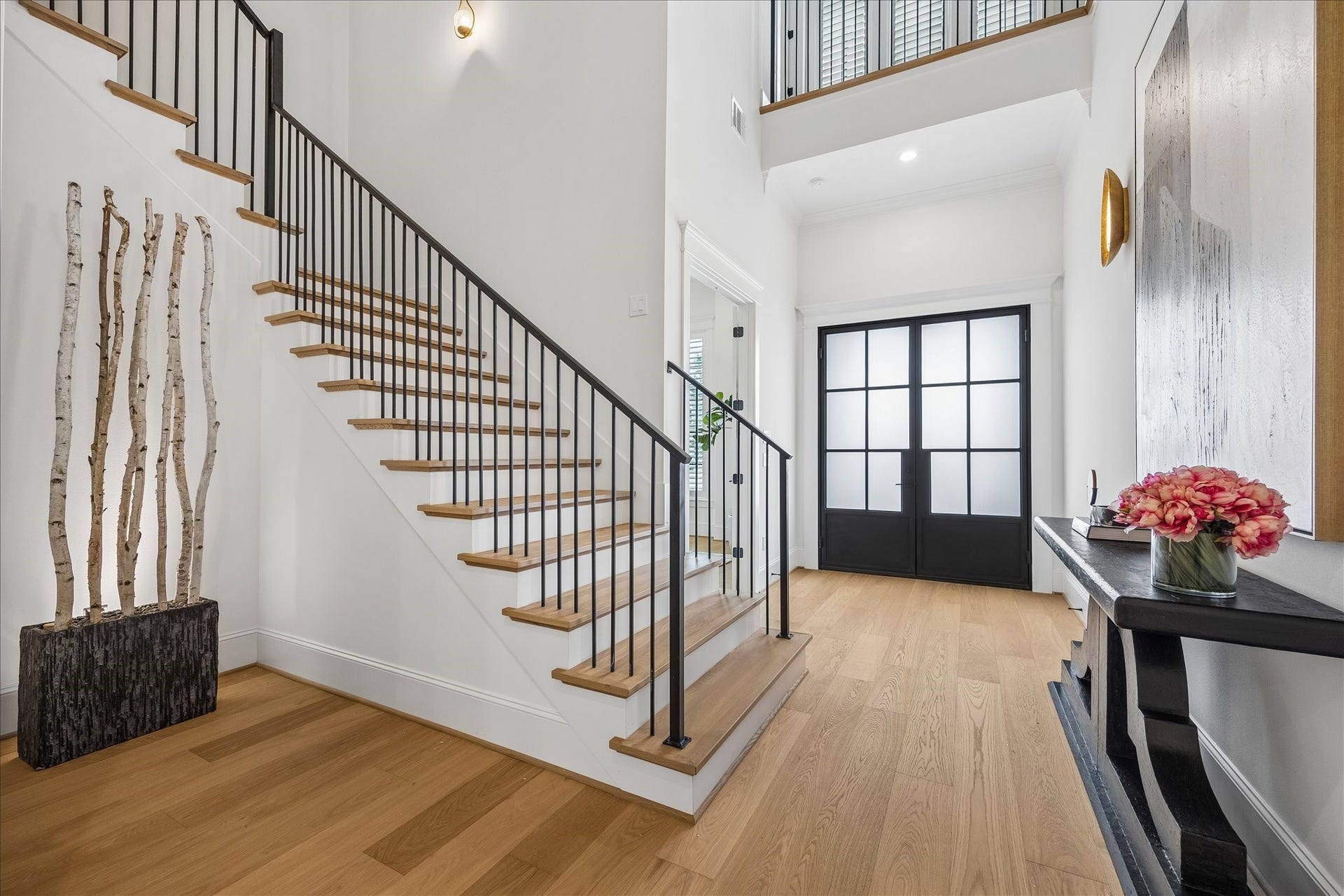 Dramatic two story foyer welcomes you with white oak flooring, warm wood stair treads and sleek iron railings. Tall windows above the entry draw natural light through the space and emphasize the impressive ceiling height.