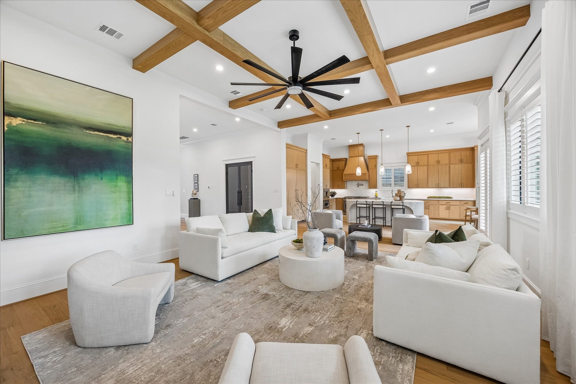 12 foot ceilings and natural wood beams give the living area impressive scale while maintaining an open connection to the kitchen and dining spaces. White oak flooring carries throughout the main living areas for a cohesive first floor design.