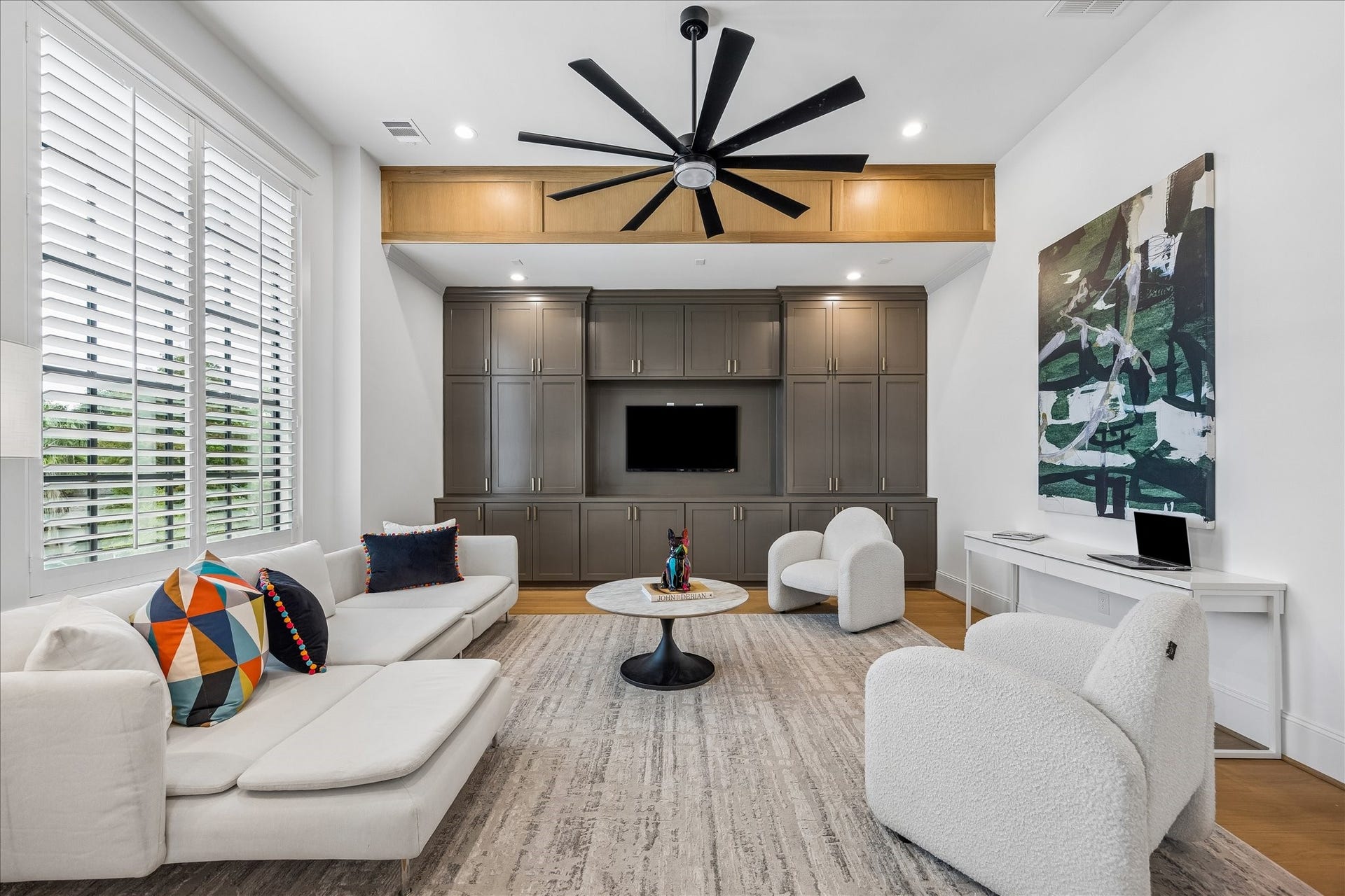 Custom built ins span the gameroom wall, providing extensive concealed storage and a polished focal point. Oversized windows bring in natural light while warm wood accents add architectural character.