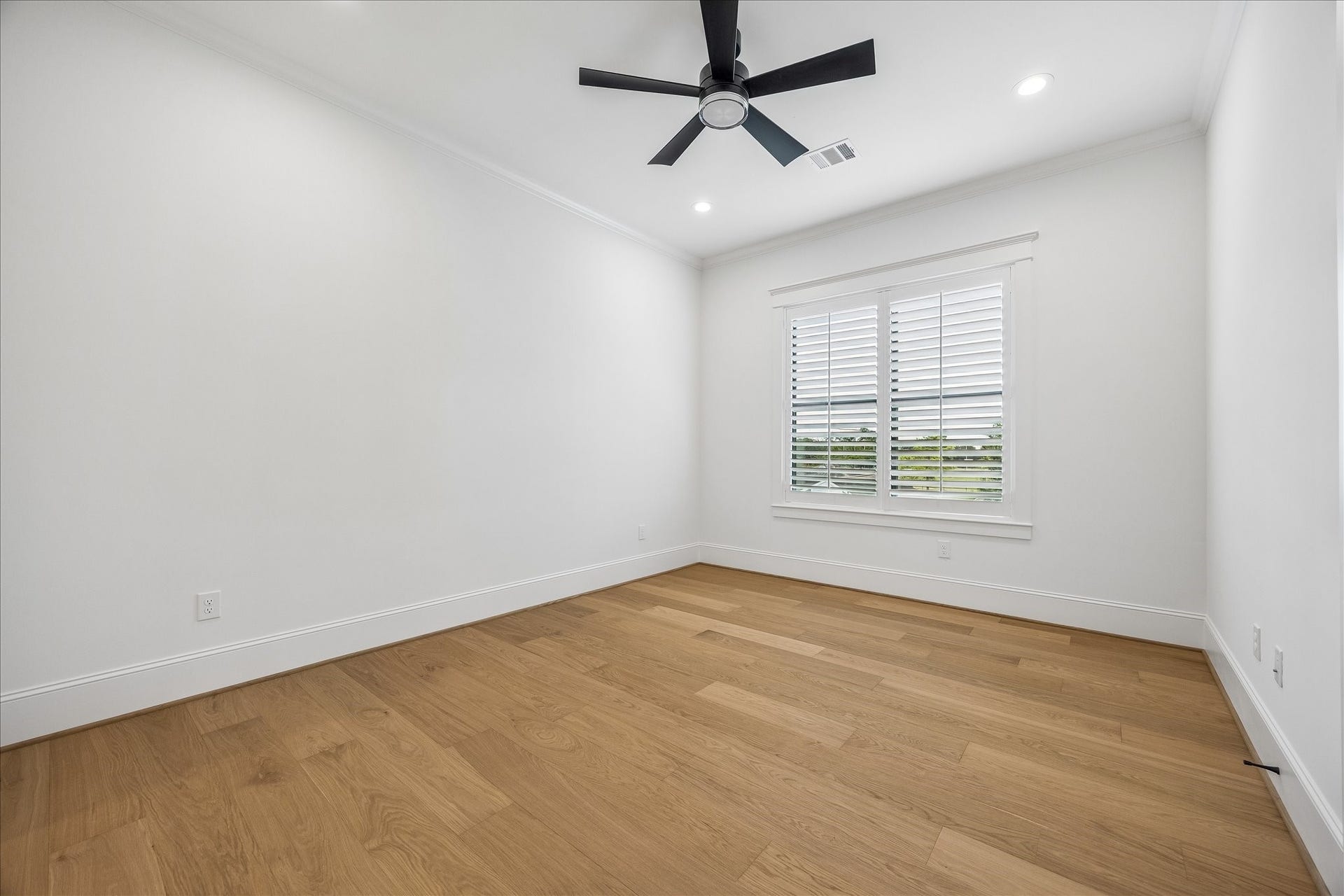 Well proportioned secondary bedroom offers hardwood flooring, high ceilings and a large shuttered window that brings in natural light while maintaining privacy.