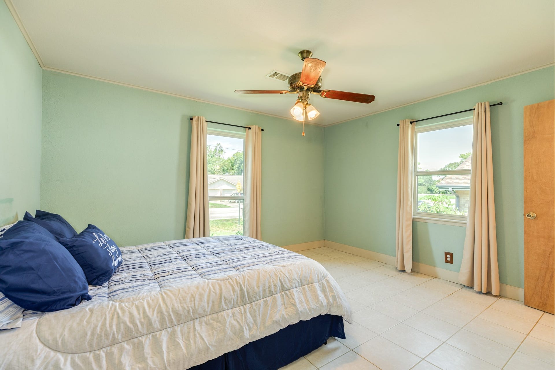 Primary bedroom feature easy-care tile flooring, ceiling fans, and windows that provide plenty of natural light with en-suite half bath and large walk-in closet.