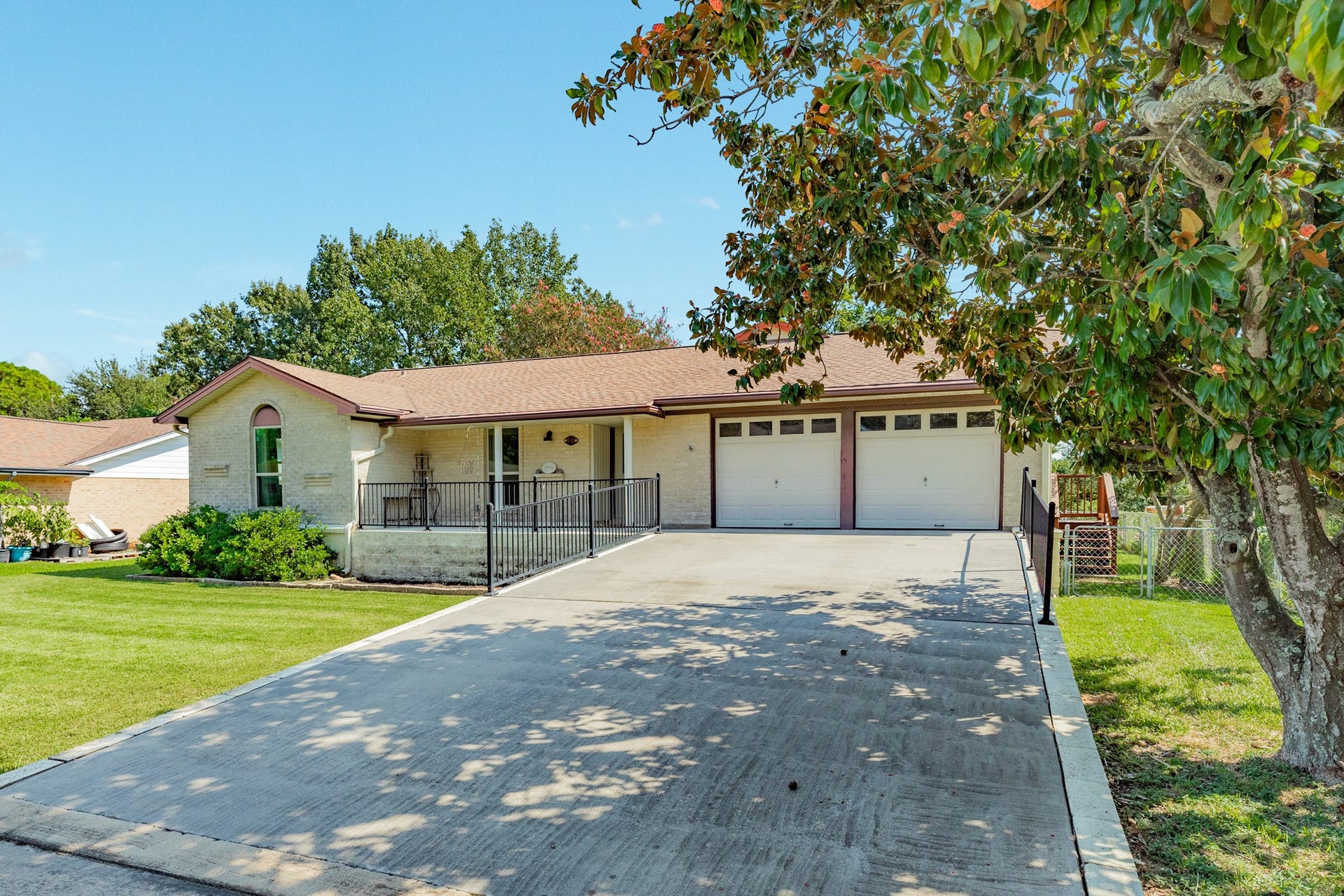 Single-story home with a light brick exterior has been raised 40 inches for peace of mind during flooding events. A spacious concrete driveway leads to the attached two-car garage and covered front porch. The generous covered entry provides a welcoming approach to the home and features a decorative glass front door.