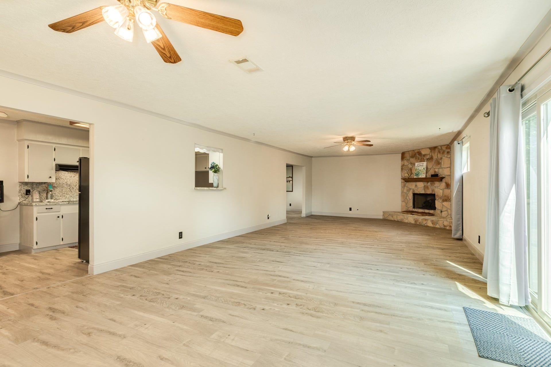 Impressively spacious family room provides an exceptional second living area highlighted by a floor-to-ceiling stone fireplace with raised hearth and wood mantel. Abundant wall space, and wood-look flooring enhance the expansive layout, while windows and a sliding glass door bring in natural light and provide direct access to the backyard deck.