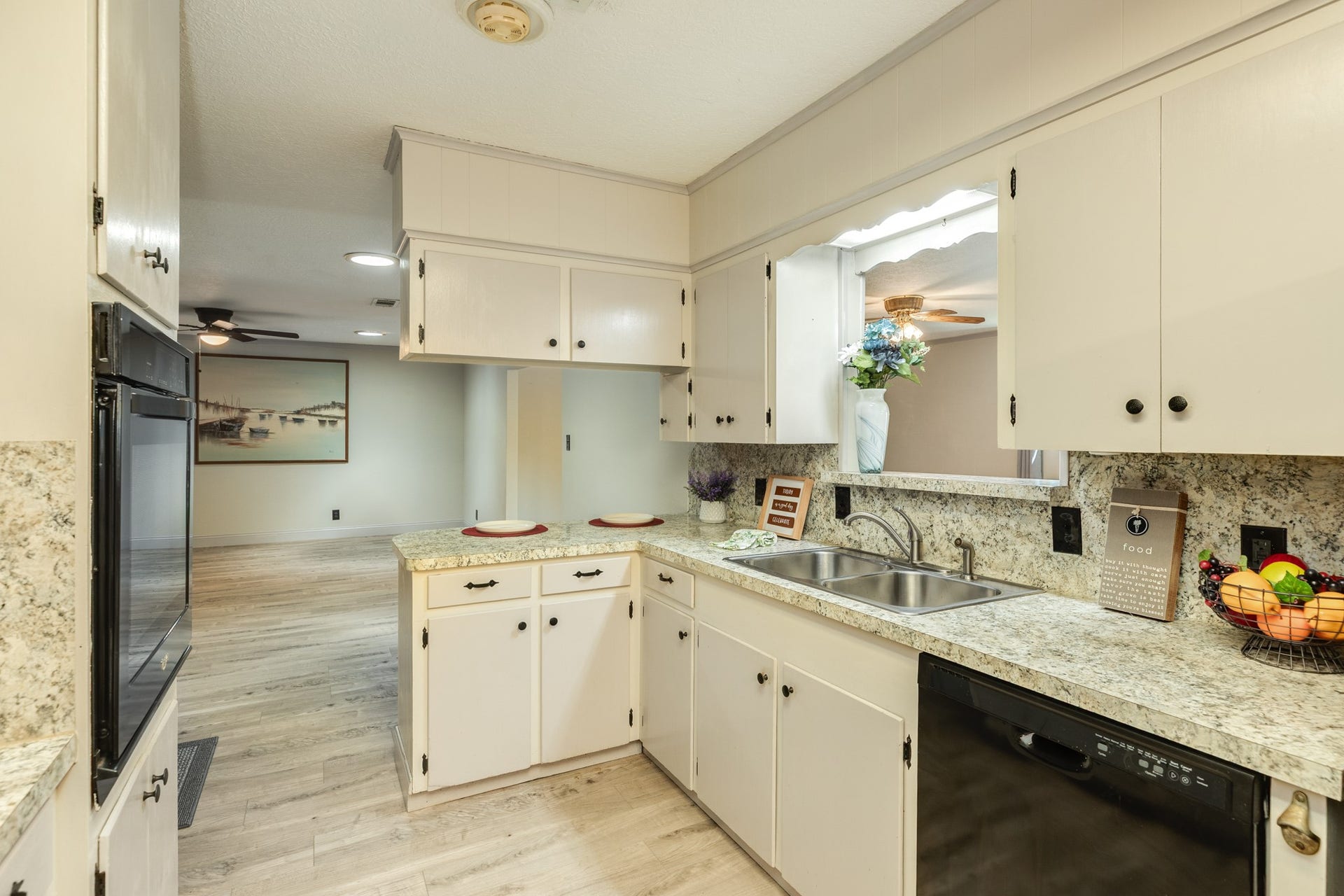 Functional kitchen features abundant cabinetry, granite-look countertops and backsplash, electric cooktop, built-in oven, dishwasher, double-basin sink. A convenient pass-through and breakfast bar provide casual seating while opening the kitchen to the main living area, creating a practical layout for meals and entertaining.