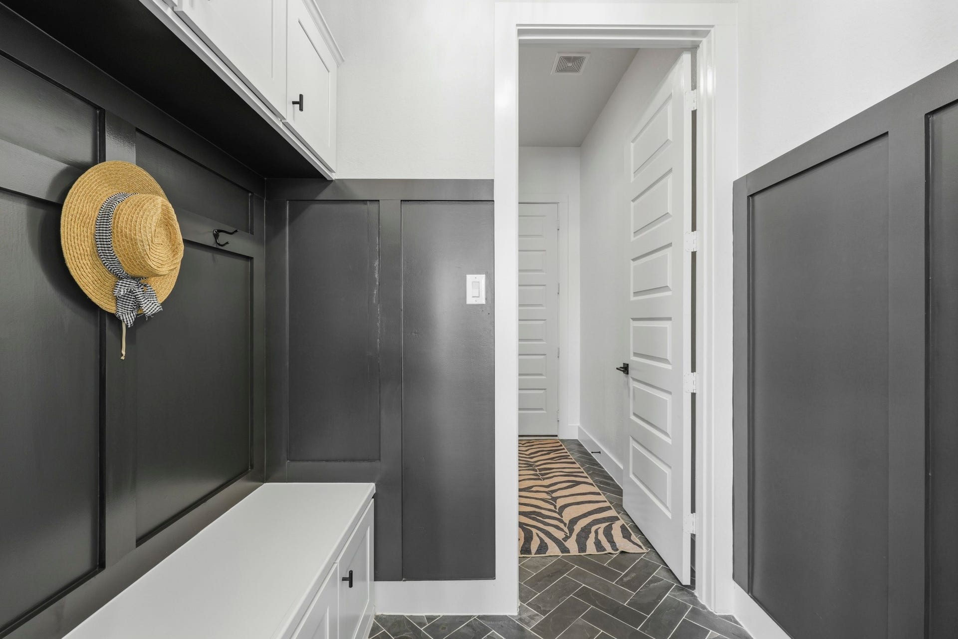 9907 Regal Bend Drive, Missouri City, TX 77459 MUD and laundry room with board & batten paneling, herringbone black slate flooring and built-in upper and lower cabinets