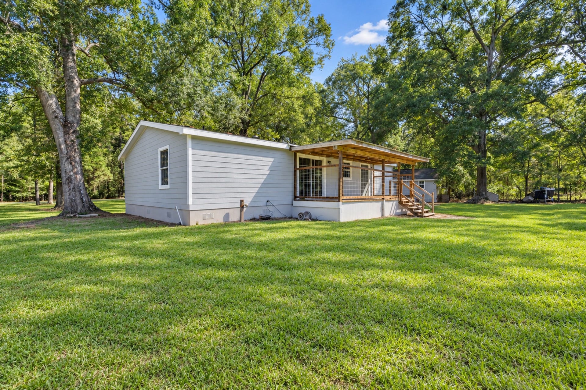 2009 Holder Rambo Road, Huffman, TX 77336 Charming home with a spacious backyard surrounded by mature trees, featuring a cozy porch perfect for relaxing outdoors.