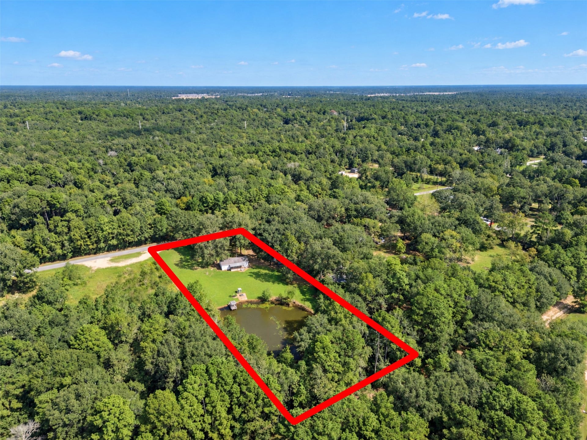 2009 Holder Rambo Road, Huffman, TX 77336 Expansive wooded property features a charming home surrounded by lush greenery and a serene pond, offering privacy and natural beauty in a tranquil setting.