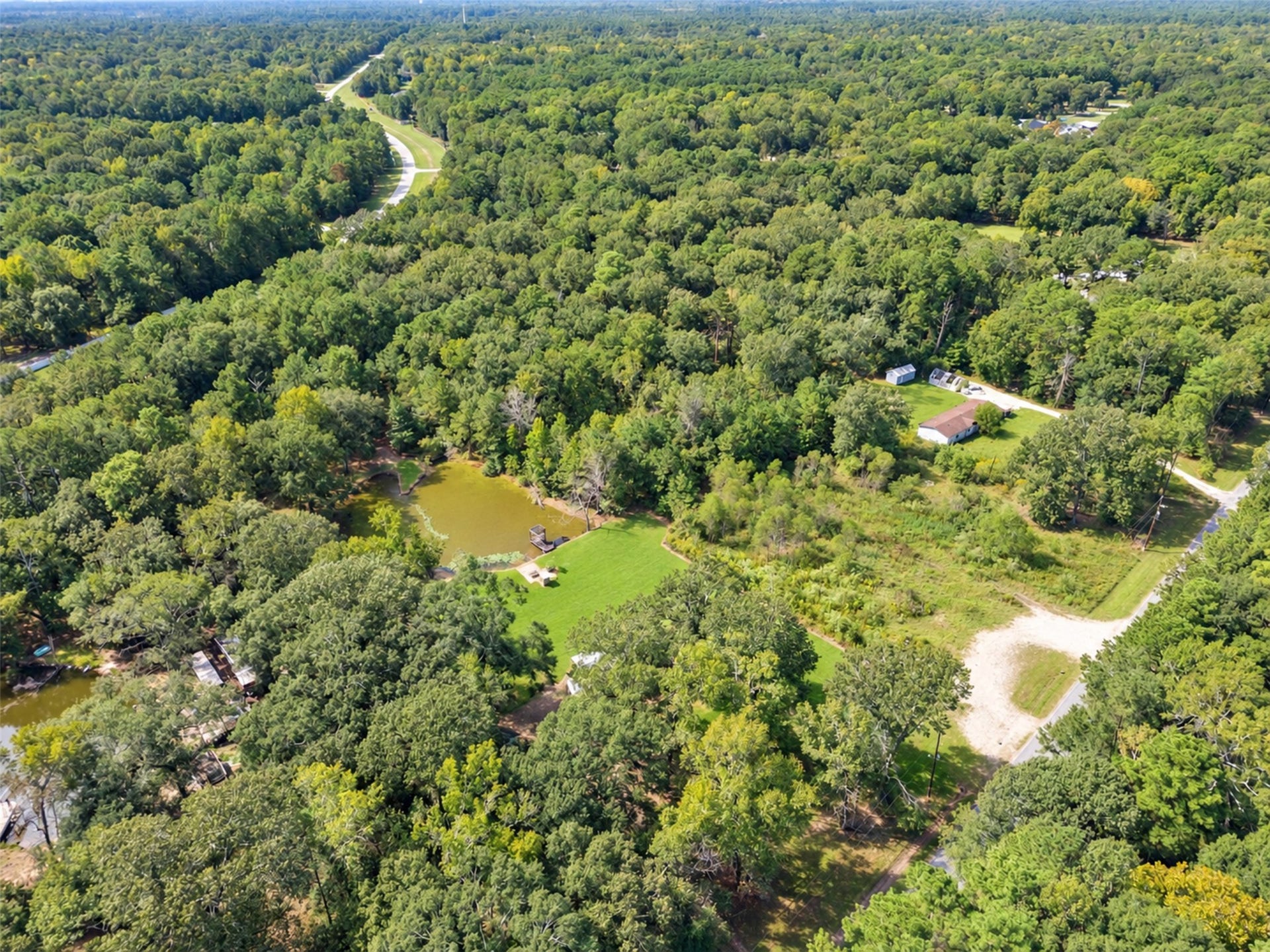 2009 Holder Rambo Road, Huffman, TX 77336 Expansive wooded property with a charming pond and open grassy areas, offering a serene and private retreat amidst nature.