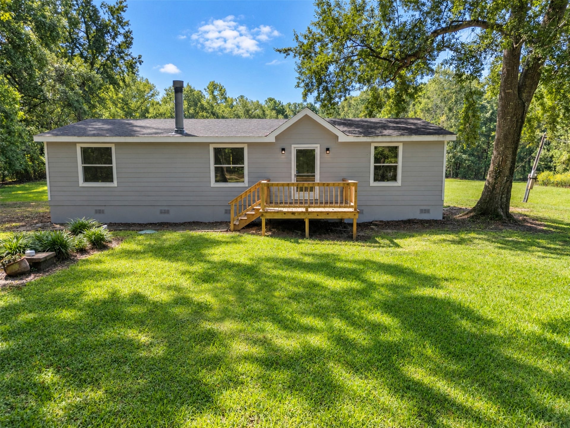 2009 Holder Rambo Road, Huffman, TX 77336 Charming single-story home with a cozy porch, nestled on a lush green lawn surrounded by mature trees, offering a serene and private setting.
