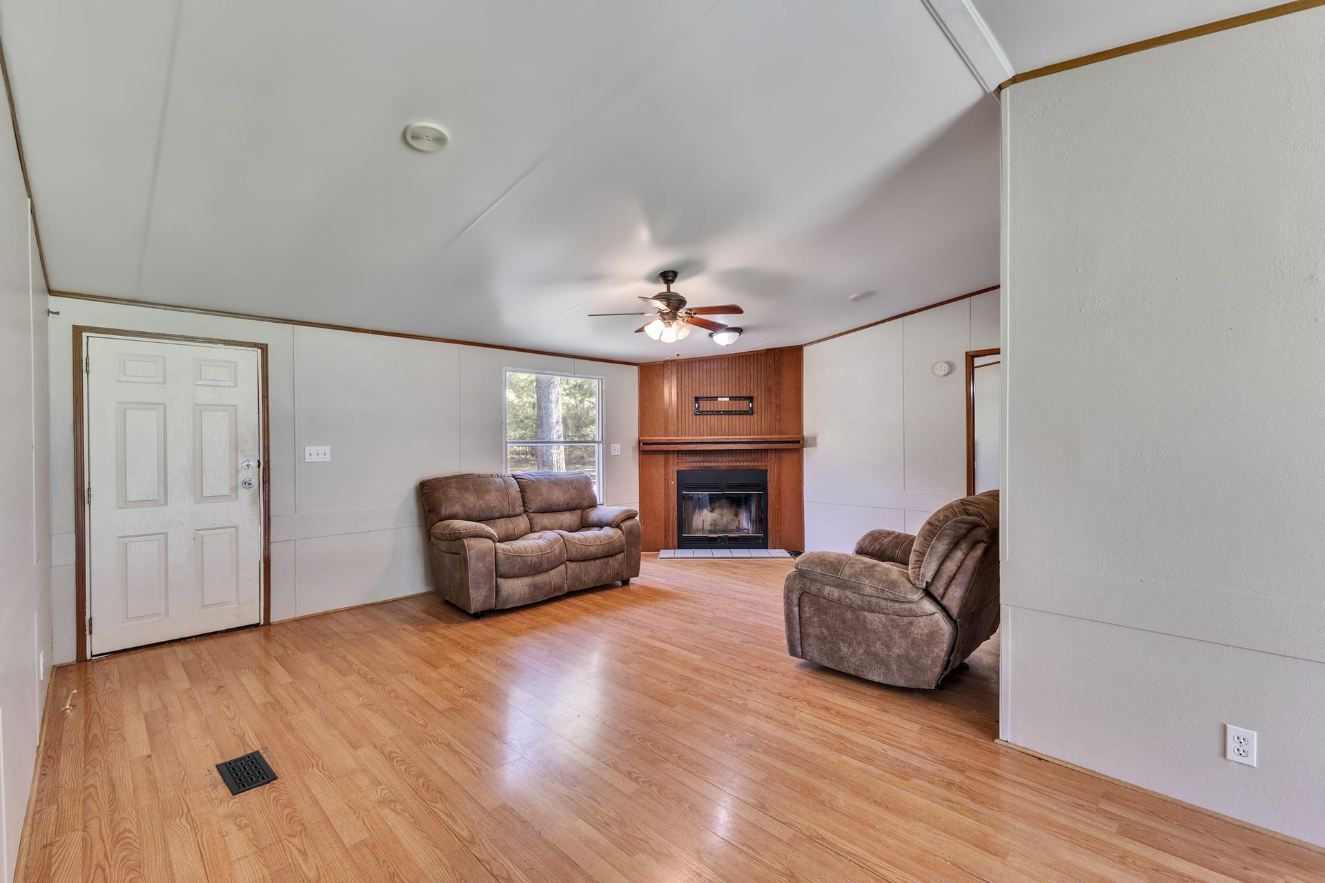 2009 Holder Rambo Road, Huffman, TX 77336 Spacious living room featuring a cozy fireplace, wood-style flooring, and ample natural light, perfect for relaxation and entertaining.