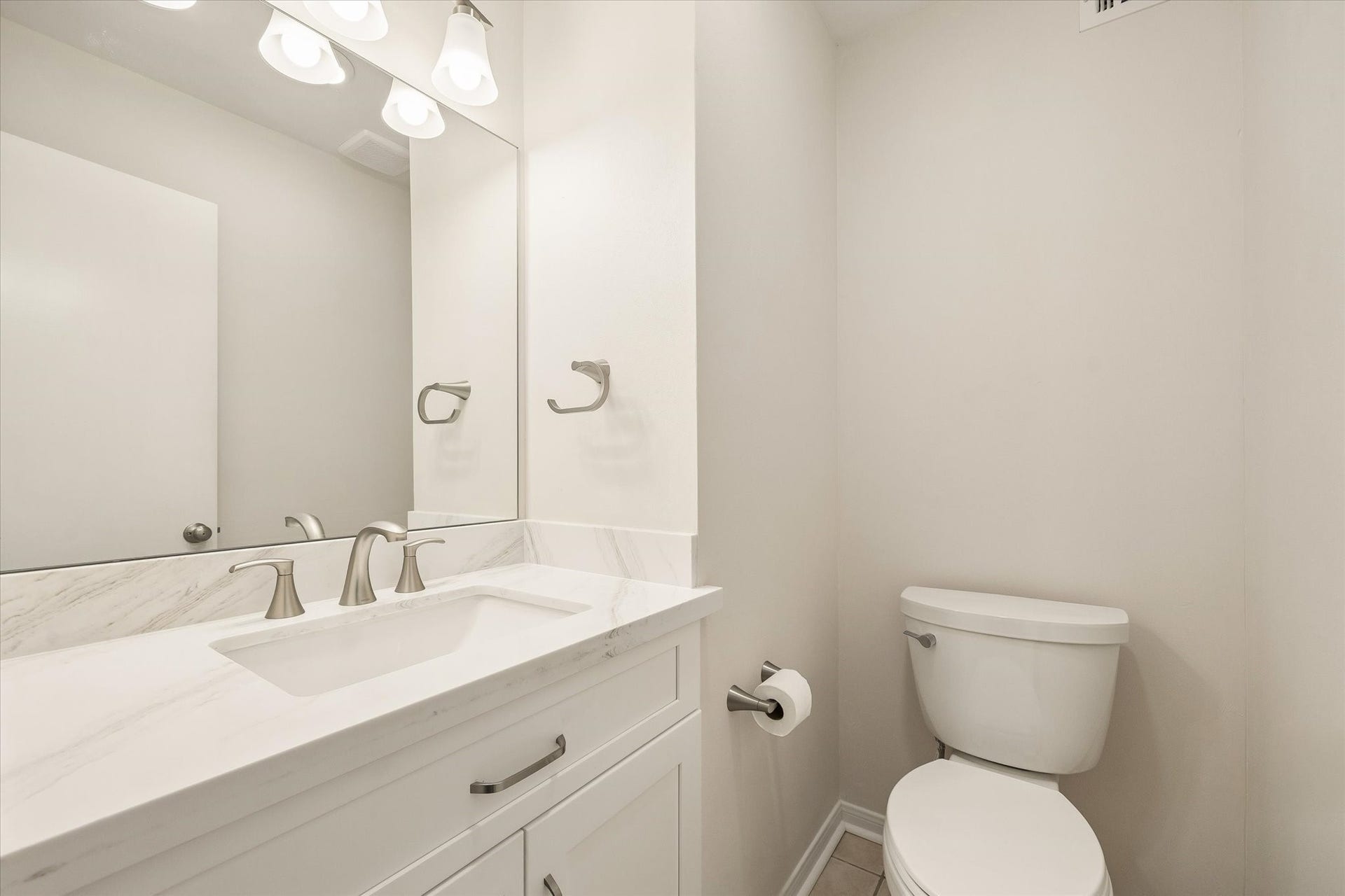 114 CAMELLIA STREET, Sugar Land, TX 77478 THE HALF BATH FEATURES A WHITE VANITY, STONE COUNTERTOP, UNDERMOUNT SINK, AND BRUSHED-NICKEL FIXTURES.