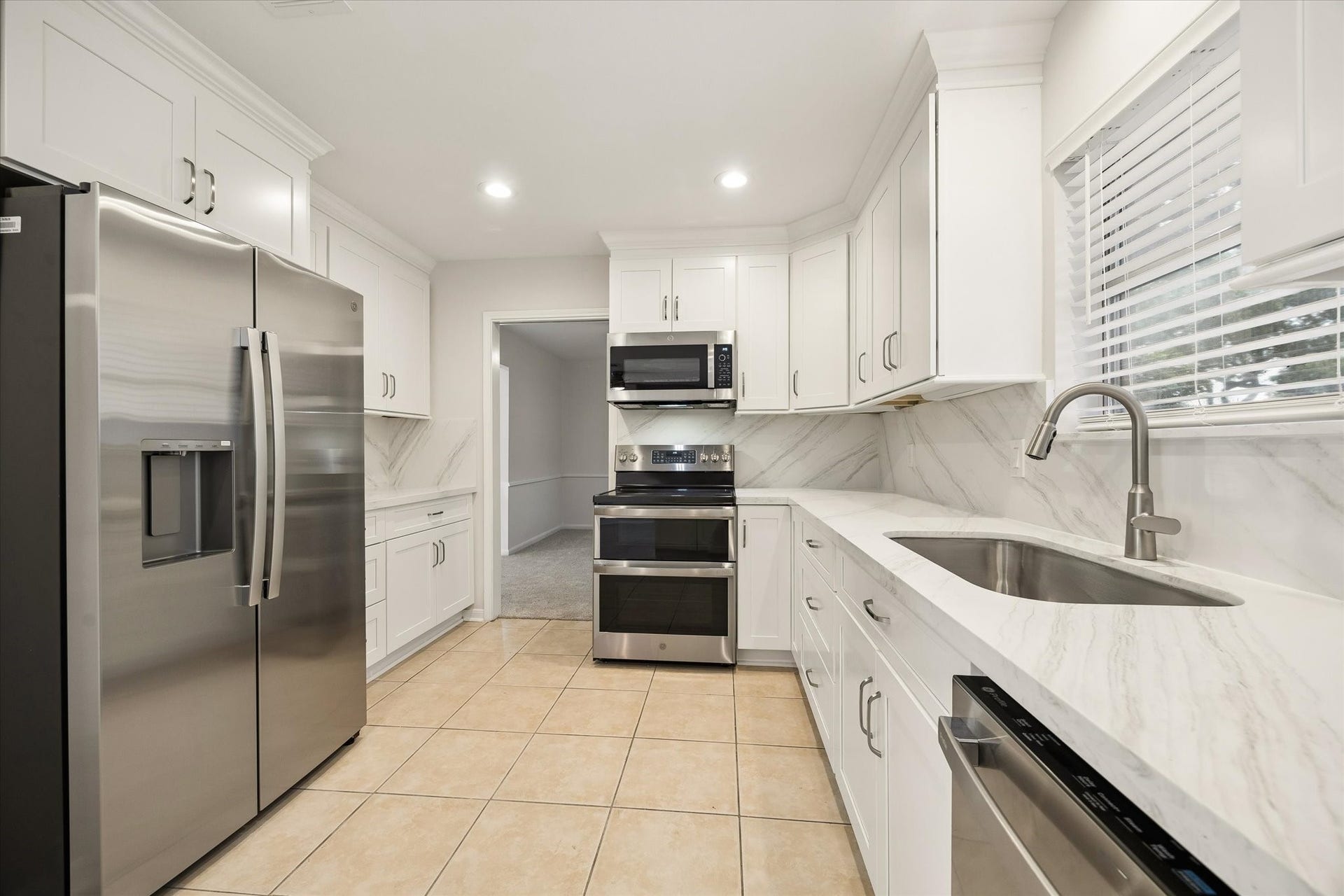114 CAMELLIA STREET, Sugar Land, TX 77478 THE BRIGHT KITCHEN IS FINISHED WITH WHITE SHAKER-STYLE CABINETRY, STONE COUNTERTOPS, A FULL-HEIGHT BACKSPLASH, STAINLESS STEEL APPLIANCES, AND AMPLE STORAGE.