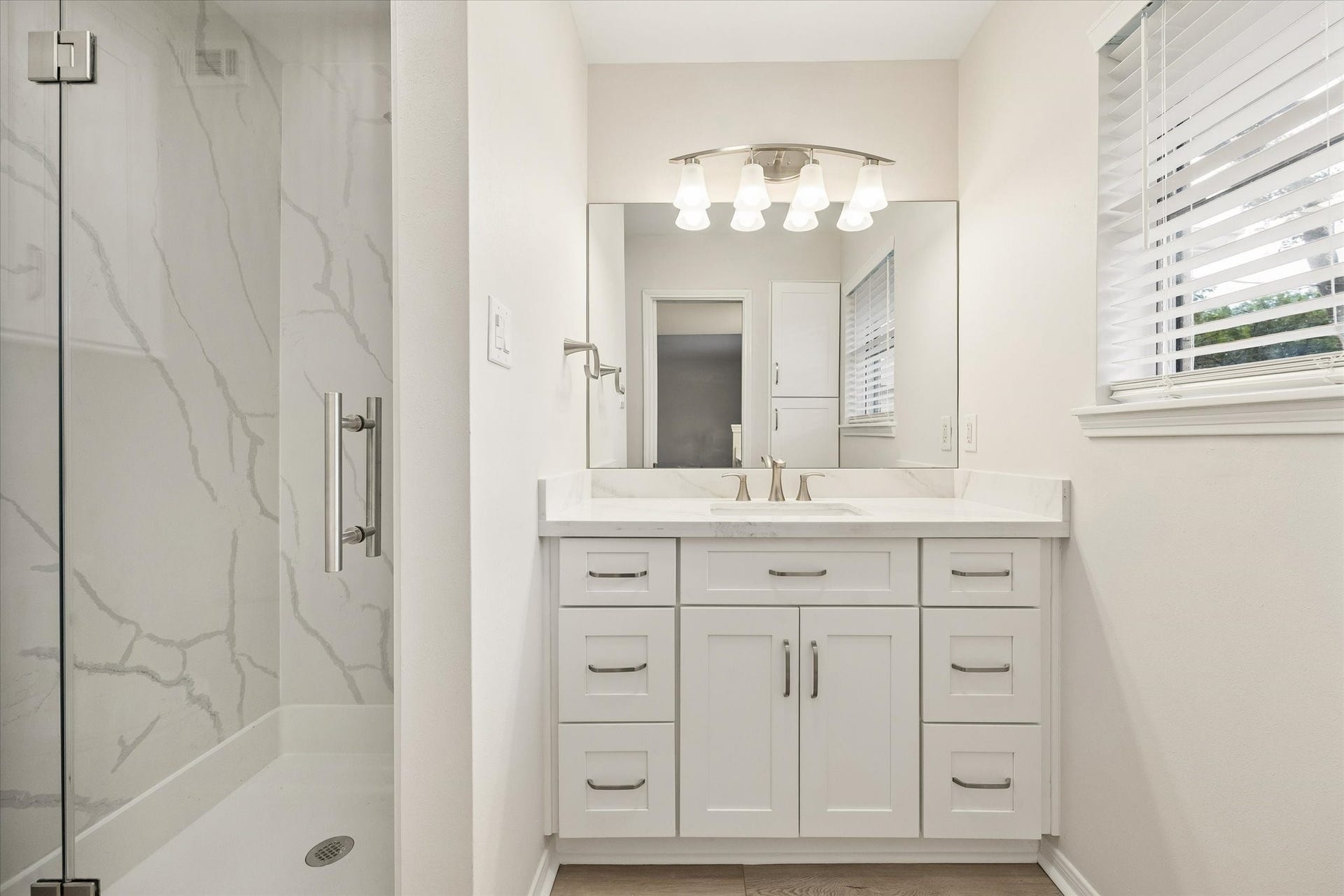 114 CAMELLIA STREET, Sugar Land, TX 77478 A SPACIOUS PRIMARY BEDROOM FEATURES NEUTRAL FINISHES, A CEILING FAN, AND A WIDE WINDOW WITH TREE-LINED VIEWS.