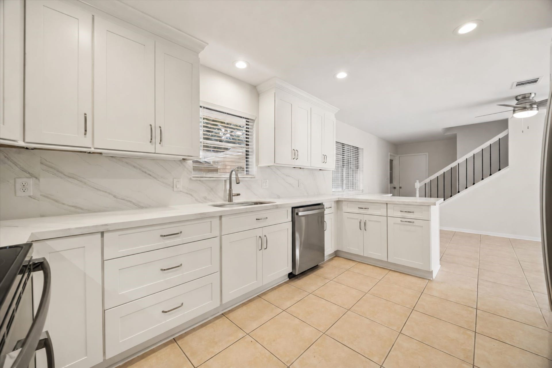 114 CAMELLIA STREET, Sugar Land, TX 77478 THE UPDATED KITCHEN OFFERS ABUNDANT WHITE CABINETRY, STONE COUNTERTOPS, A FULL-HEIGHT BACKSPLASH, STAINLESS STEEL APPLIANCES, AND RECESSED LIGHTING.