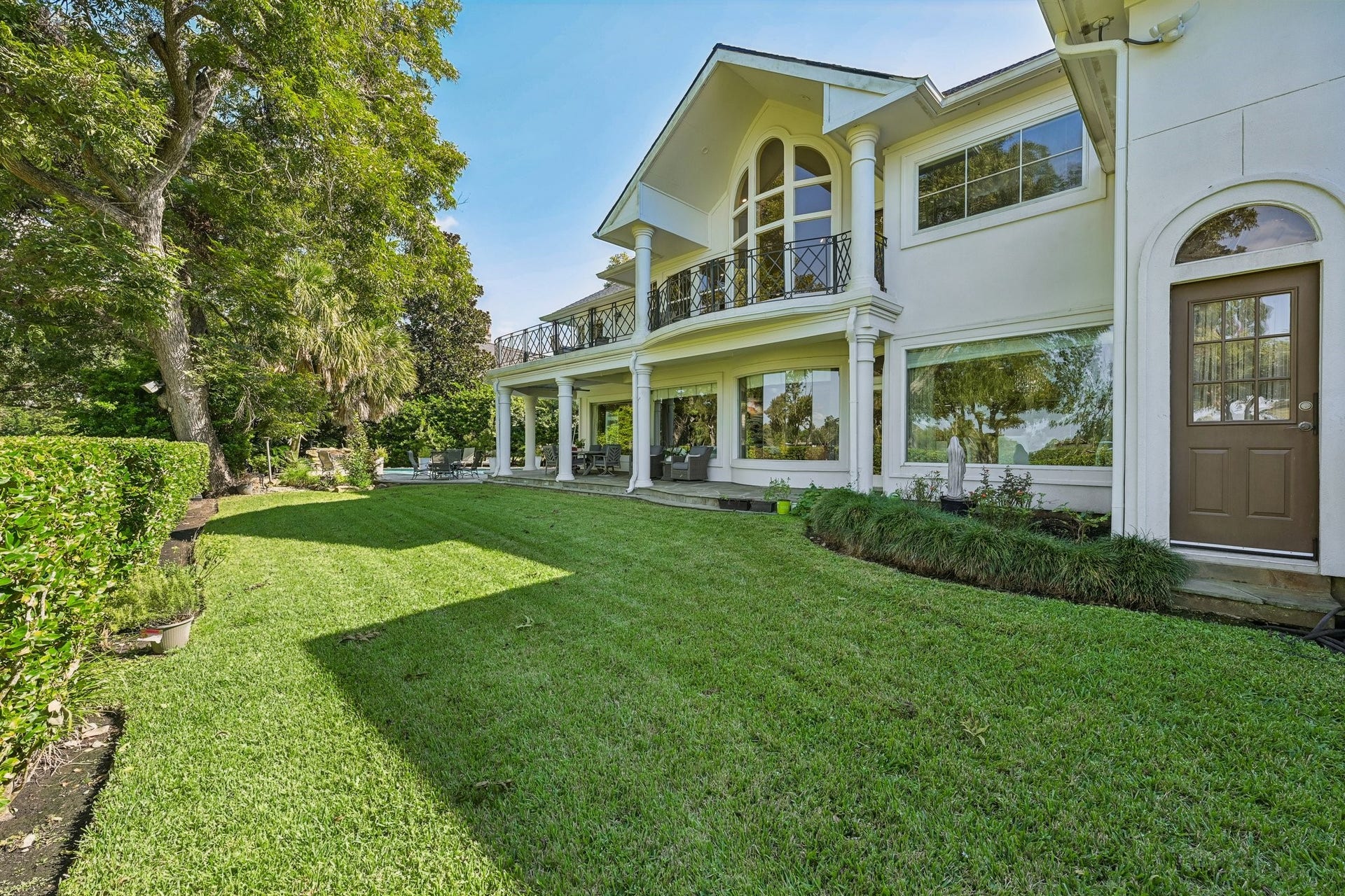 Expansive backyard featuring a generous stretch of green space, mature landscaping, and a covered patio, with additional room to enjoy the outdoors alongside the resort-style pool (Virtually Staged)