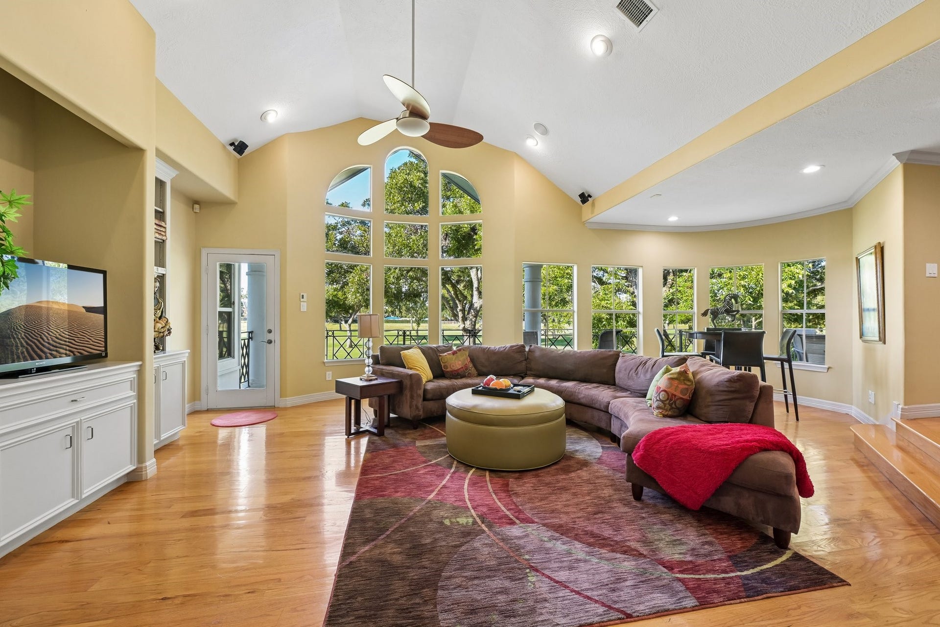 Versatile upstairs living area featuring soaring ceilings, expansive windows, built-in cabinetry, and generous lounge space, ideal for relaxing or gathering with family and friends