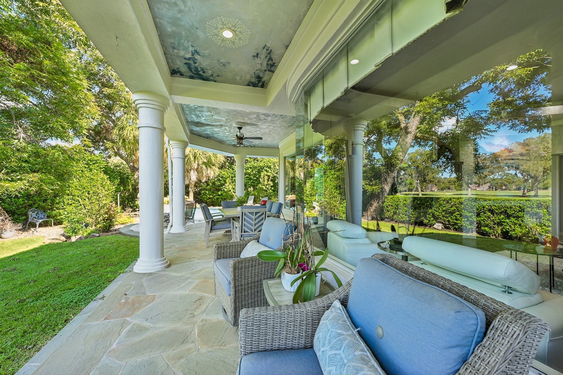 Inviting covered outdoor lounge, a decorative ceiling, and expansive windows overlooking the landscaped grounds, offering a peaceful extension of the home's living space