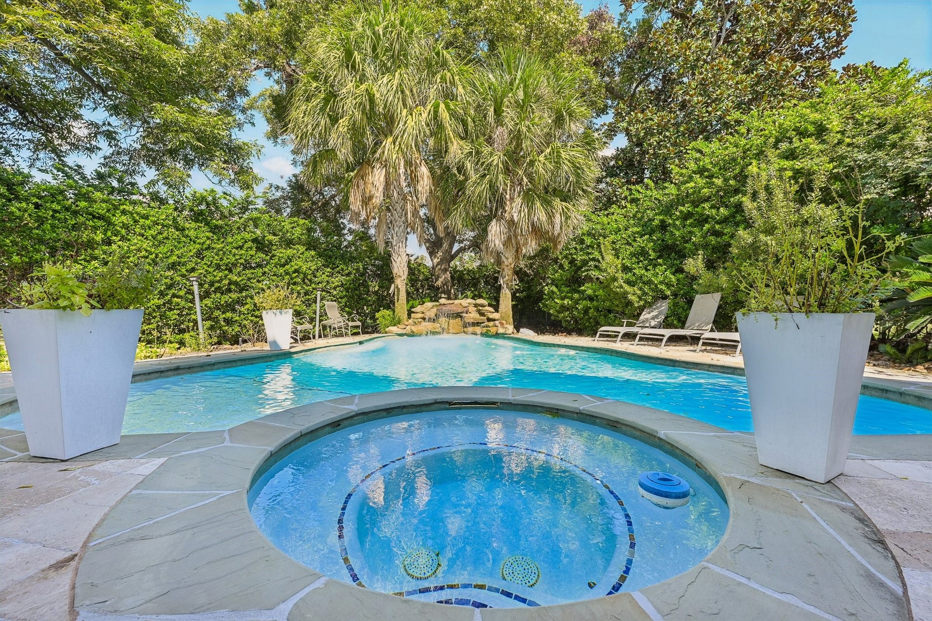 Inviting backyard oasis with an attached circular spa and expansive swimming pool, creating a private retreat for relaxation and outdoor enjoyment