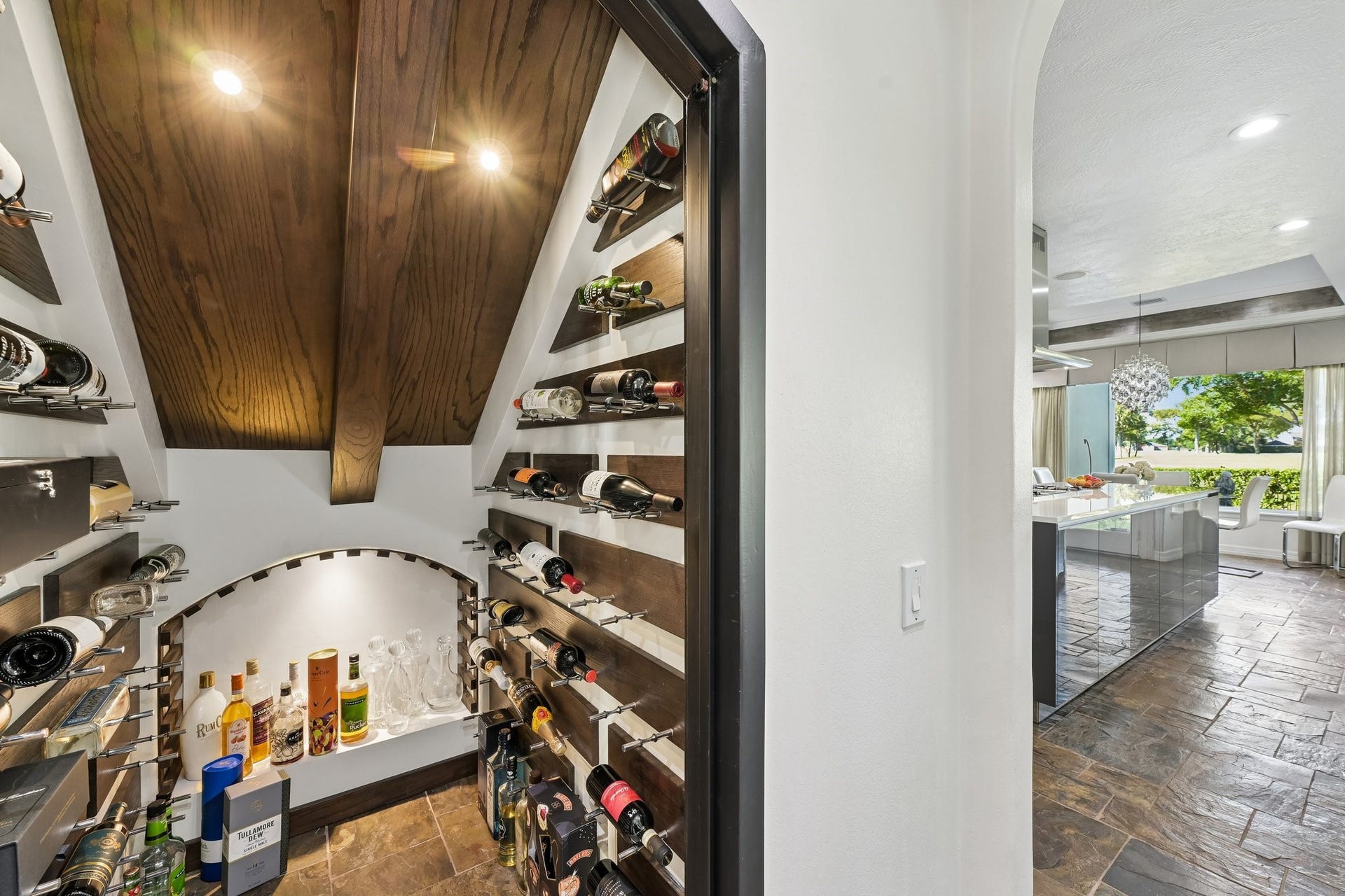 Dedicated wine cellar featuring custom wine storage, built-in shelving, and a warm wood-plank ceiling with accent lighting