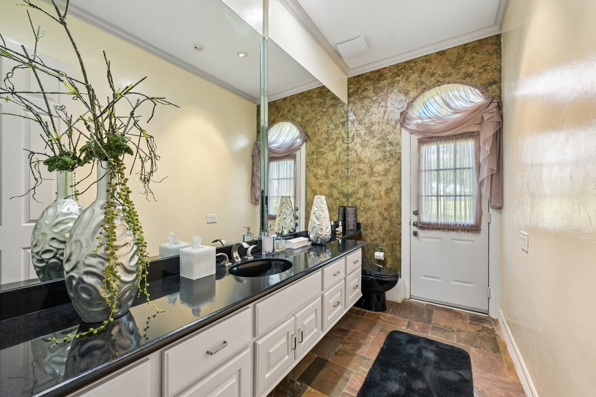 First-floor half bath featuring an extended vanity with dual sinks and direct outdoor access to the pool, ideal for added convenience when entertaining