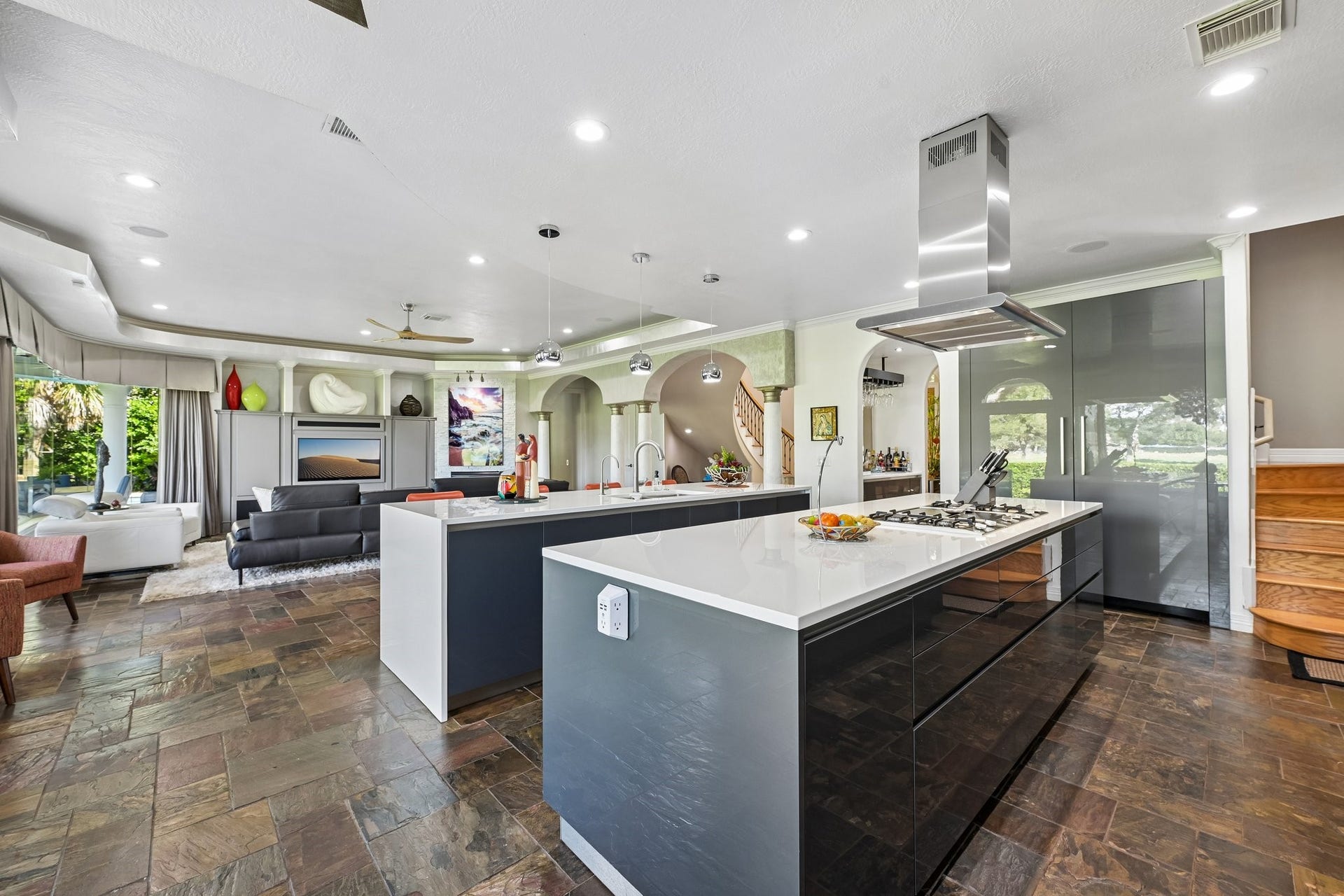 Expansive kitchen showcasing a waterfall island, gas cooktop, Nano glass countertops, and generous workspace, with an open view into the living area