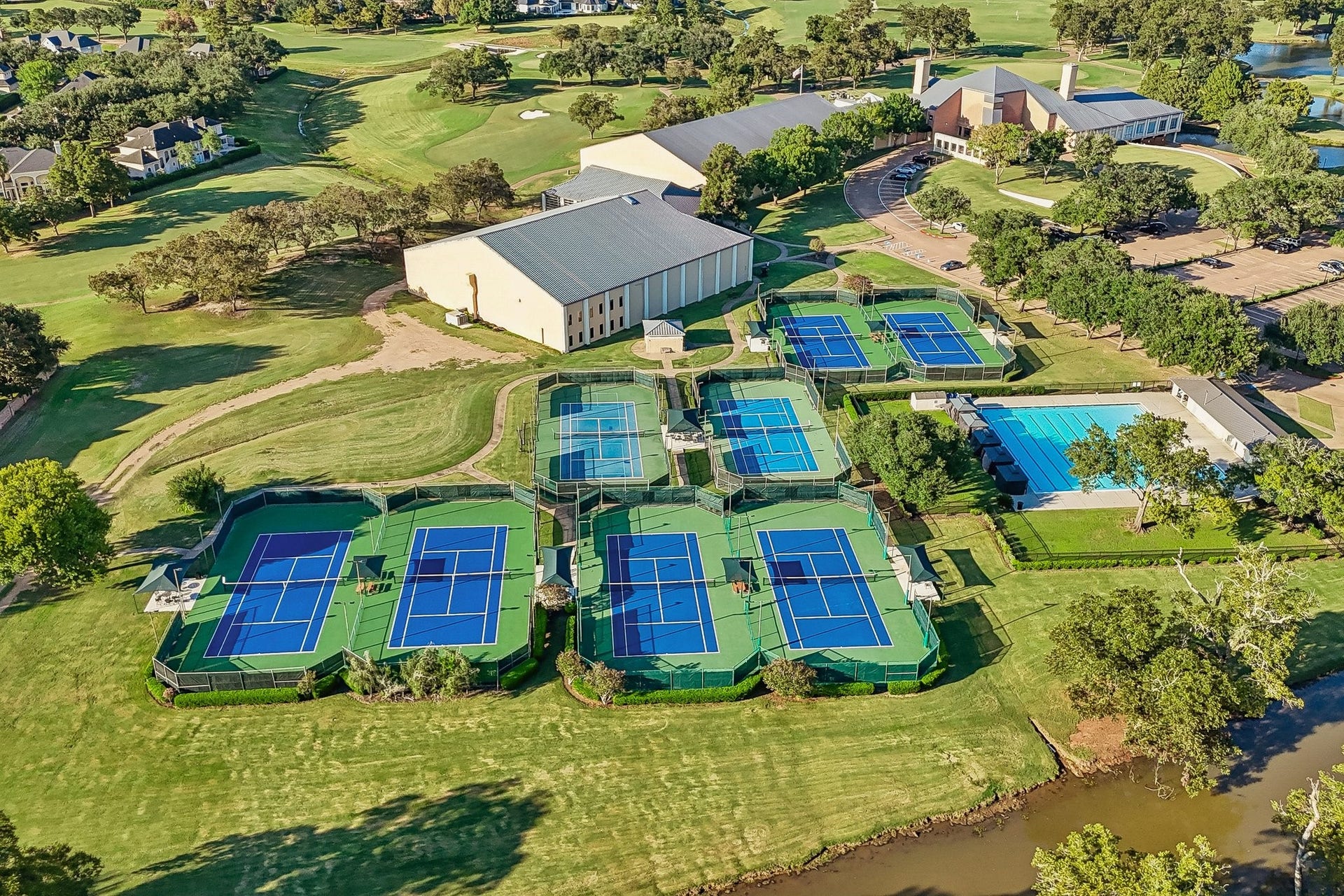 Aerial view of TPC Houstons extensive tennis facilities, showcasing multiple outdoor courts surrounded by landscaped grounds
