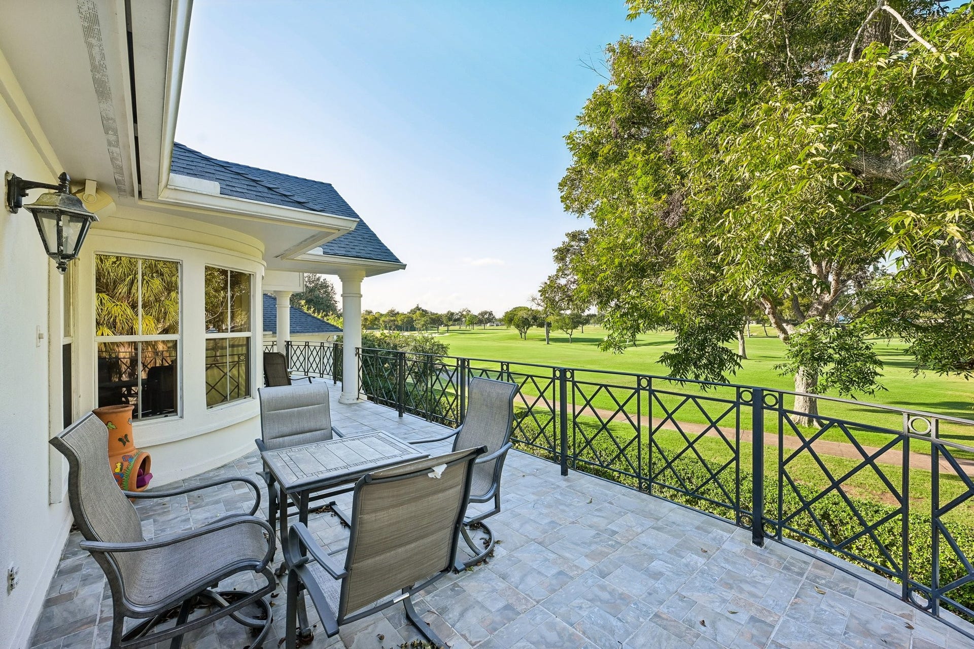 Private upstairs balcony extending from the living area, featuring a spacious outdoor seating area, decorative iron railing, and sweeping views of the TPC Houston golf course