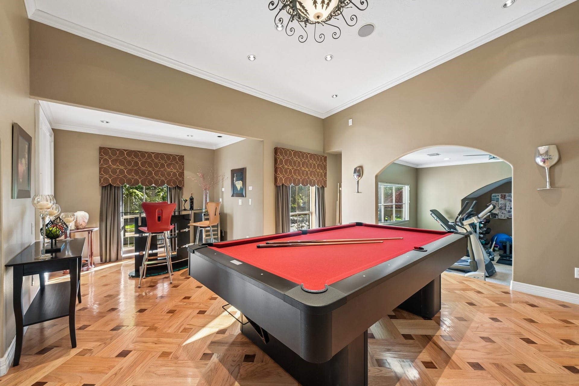 Upstairs game room featuring a full-size pool table, hardwood flooring, and an adjoining fitness area, creating a versatile space for recreation and entertaining