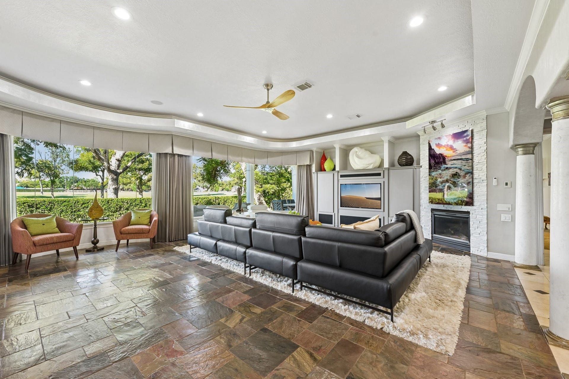 Expansive living area with floor-to-ceiling windows overlooking the TPC Houston golf course, filling the space with natural light and scenic green views