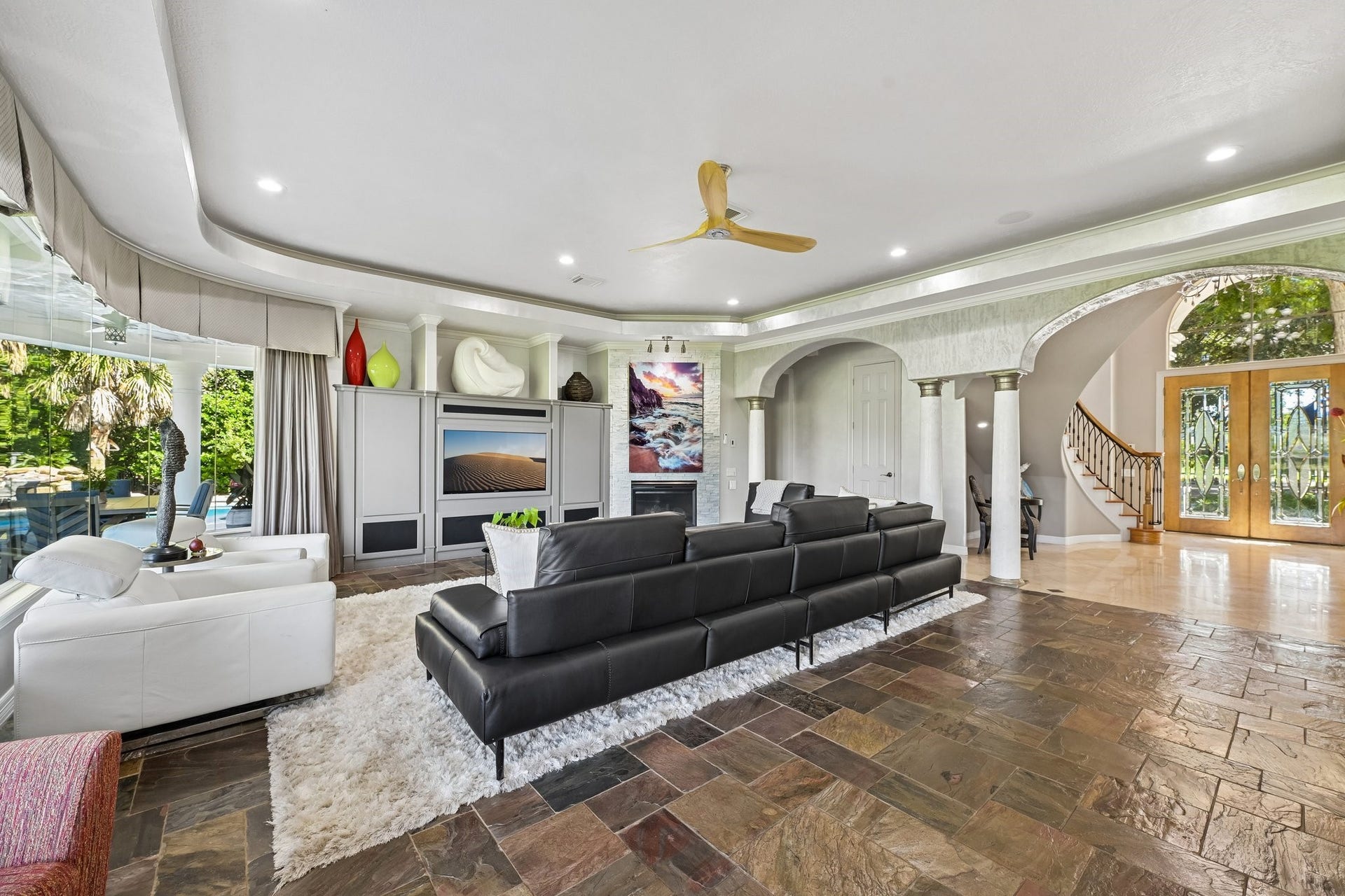 Spacious living room featuring built-in display cabinetry, and elegant arched openings connecting to the grand foyer