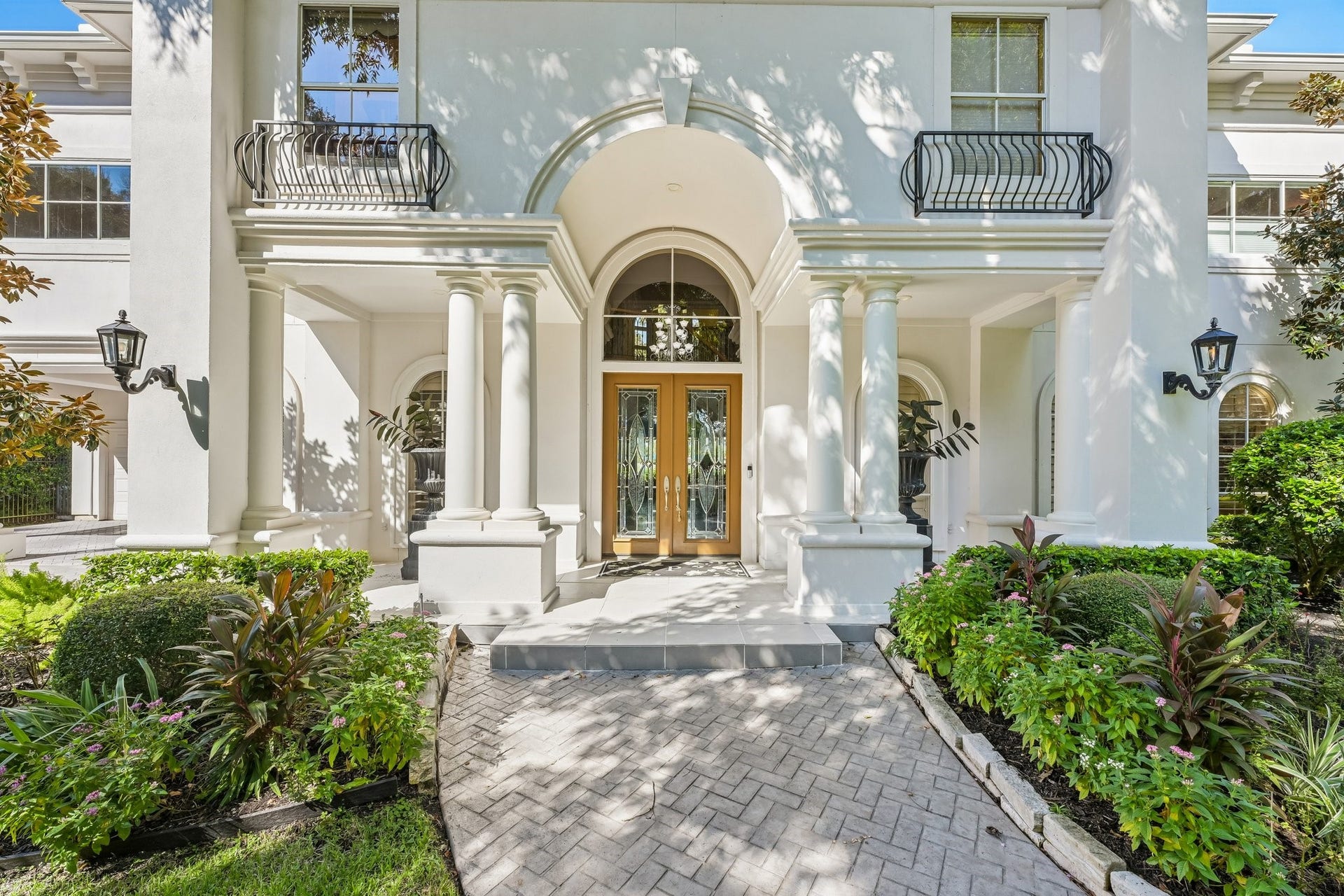 Grand front entrance showcasing a dramatic arched entryway, stately columns, elegant double doors, and decorative wrought-iron window railings