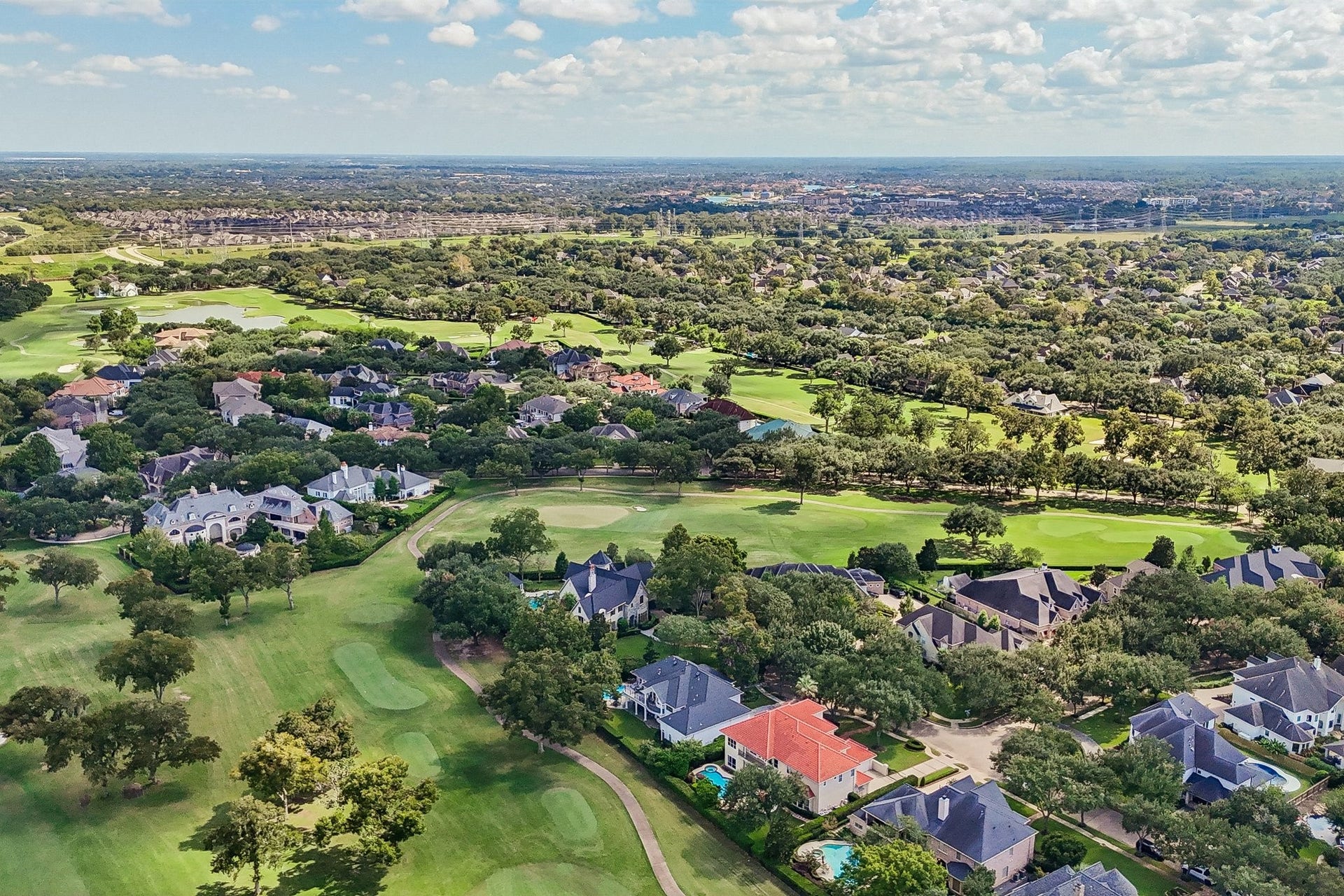 Aerial view of the Sweetwater neighborhood, showcasing expansive golf course fairways, mature trees, and the surrounding residential setting