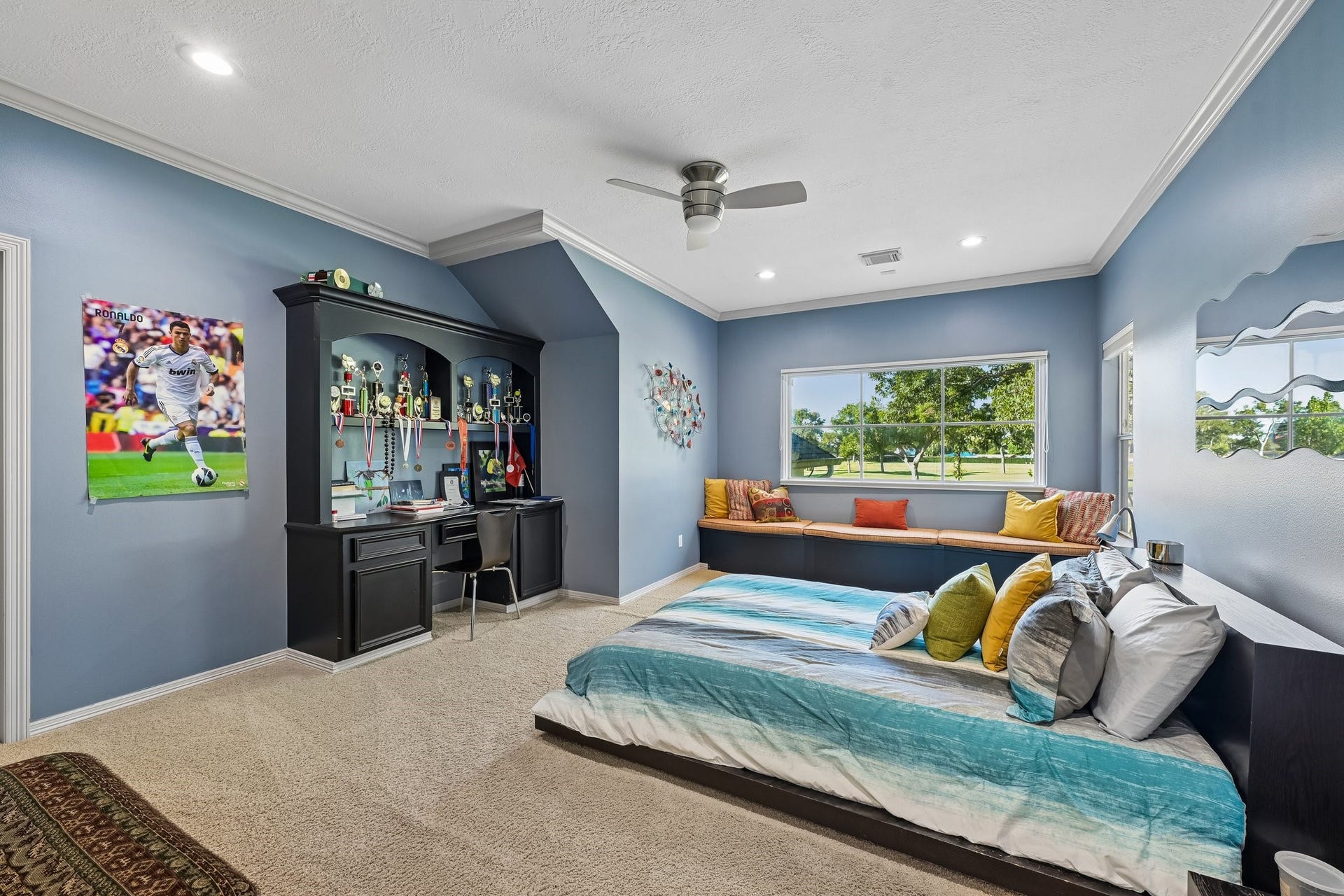 Secondary bedroom featuring a built-in desk and display cabinetry, a window-side bench, and a spacious layout with plenty of room to personalize