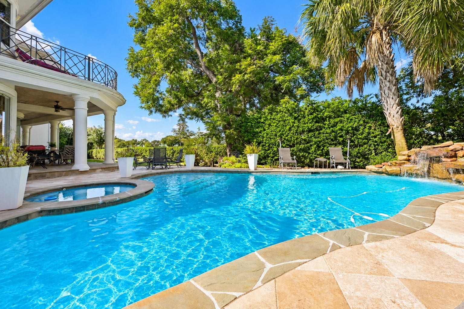 Private backyard retreat featuring a sparkling lagoon pool, relaxing spa, and tranquil waterfall surrounded by mature greenery