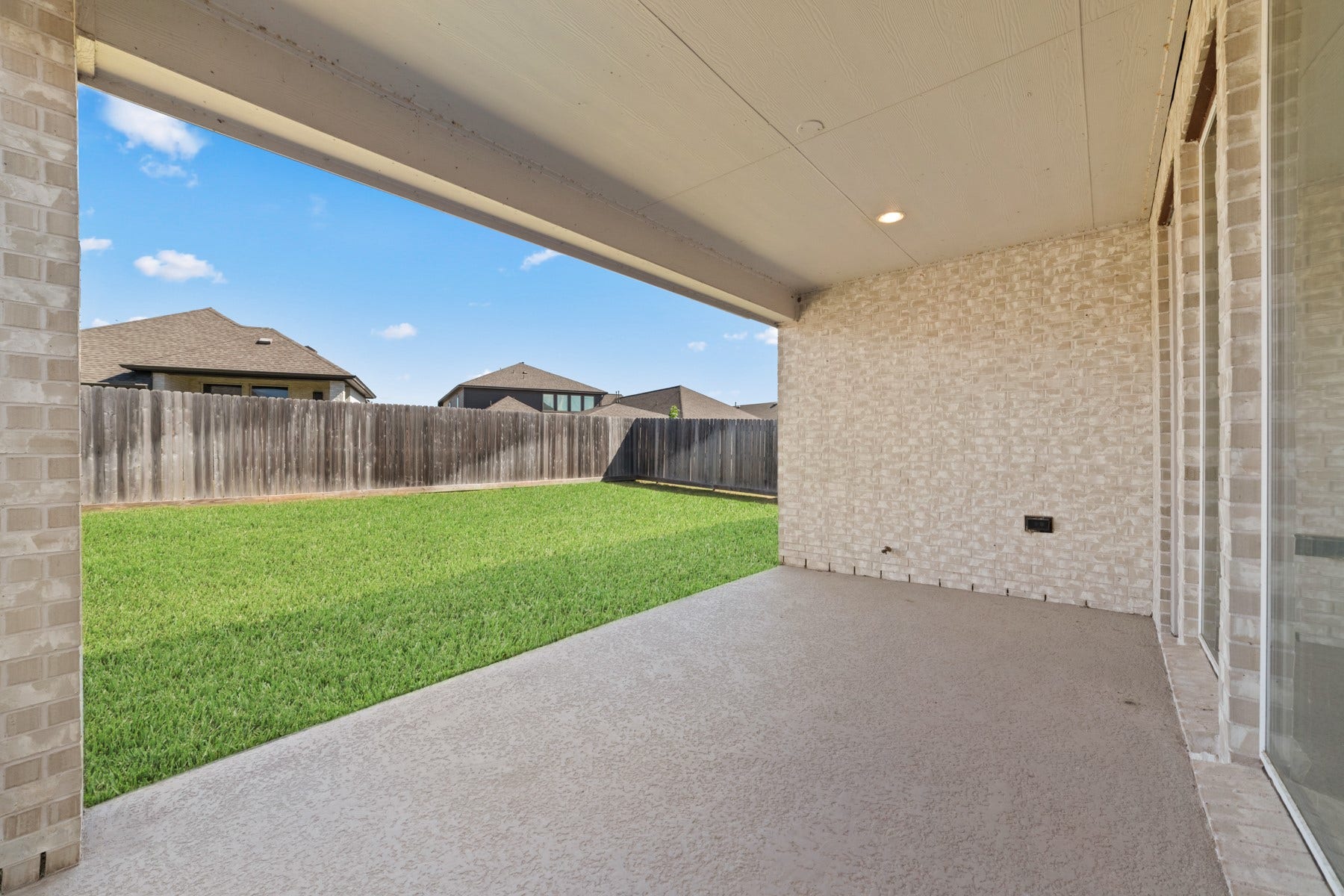 Spacious covered patio overlooking a lush, private backyard, perfect for outdoor relaxation and entertaining.