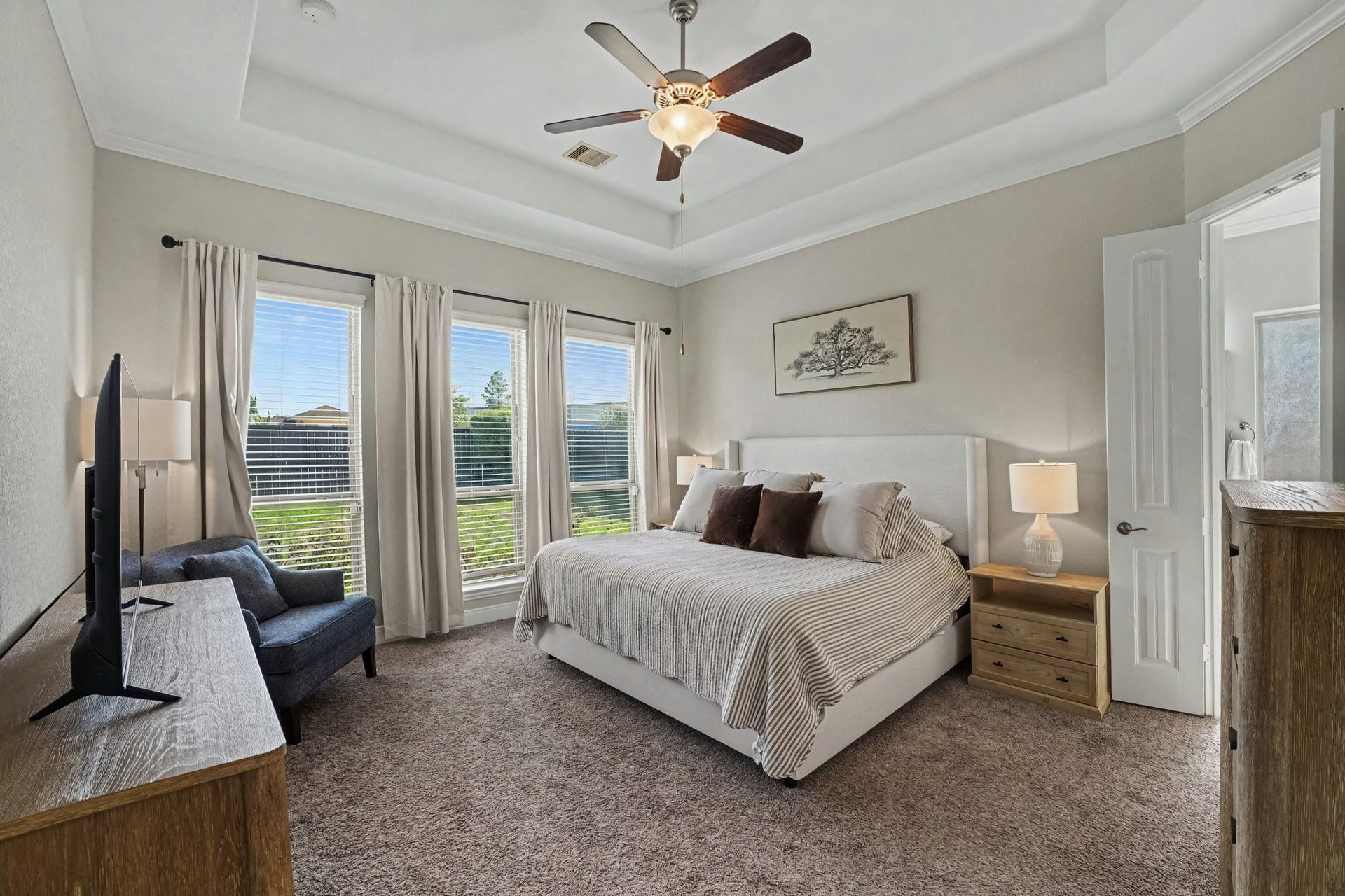 26438 Morgan Creek Lane, Katy, TX 77494 Three large floor-to-ceiling windows equipped with privacy blinds and flowing neutral drapes flood the bedroom with soft daylight while providing pleasant views of the lush backyard.