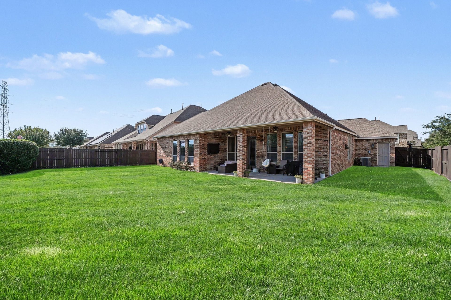 26438 Morgan Creek Lane, Katy, TX 77494 Beyond the patio stretches a vibrant, lush green lawn enclosed by sturdy wooden privacy fencing on all sides, providing a safe, open space for pets, gardens, or even a future swimming pool.