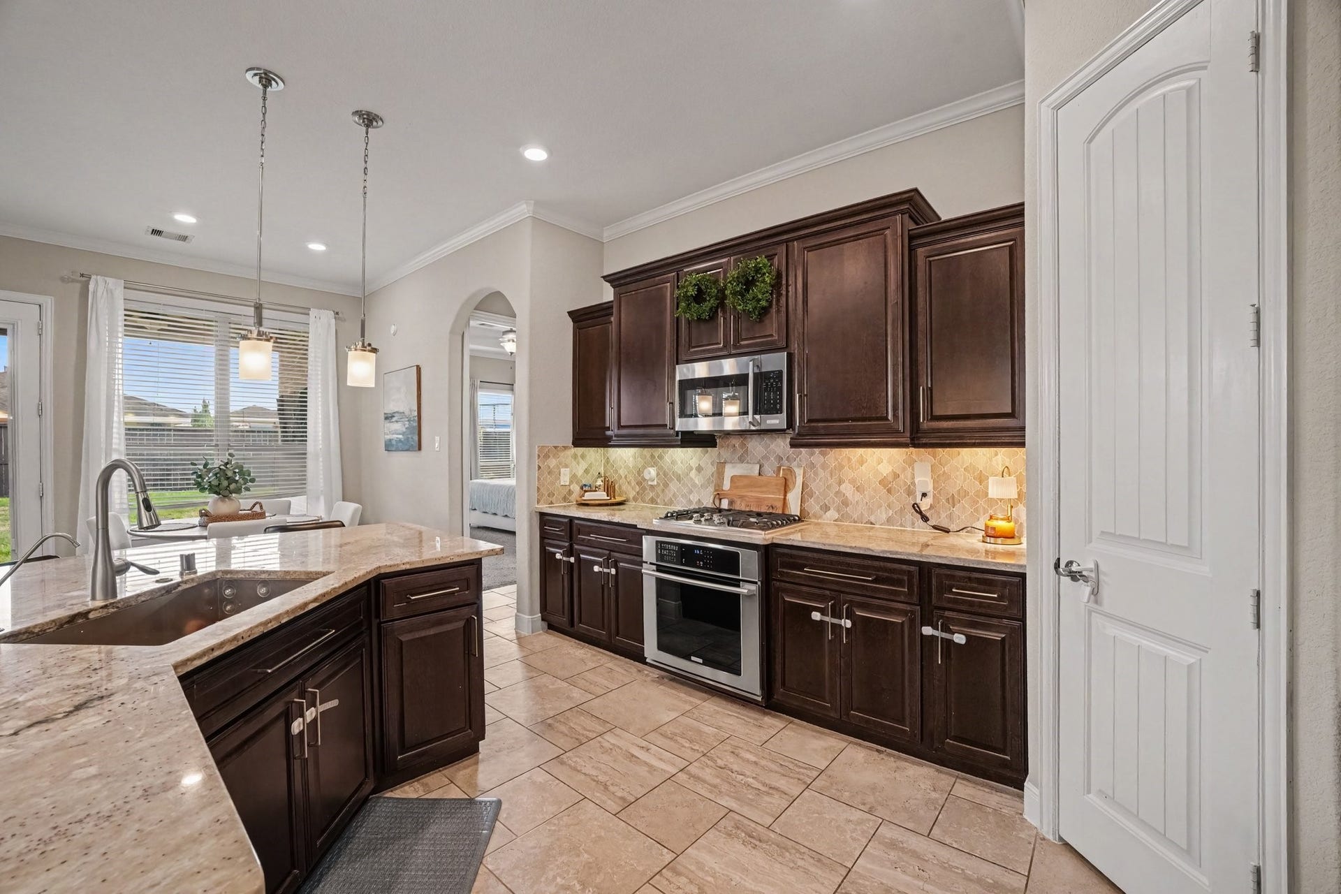 26438 Morgan Creek Lane, Katy, TX 77494 Rich dark wood cabinetry provides abundant storage, beautifully contrasted by warm patterned tile backsplashes, under-cabinet lighting, and sleek stainless steel appliances, including a built-in microwave and gas range.