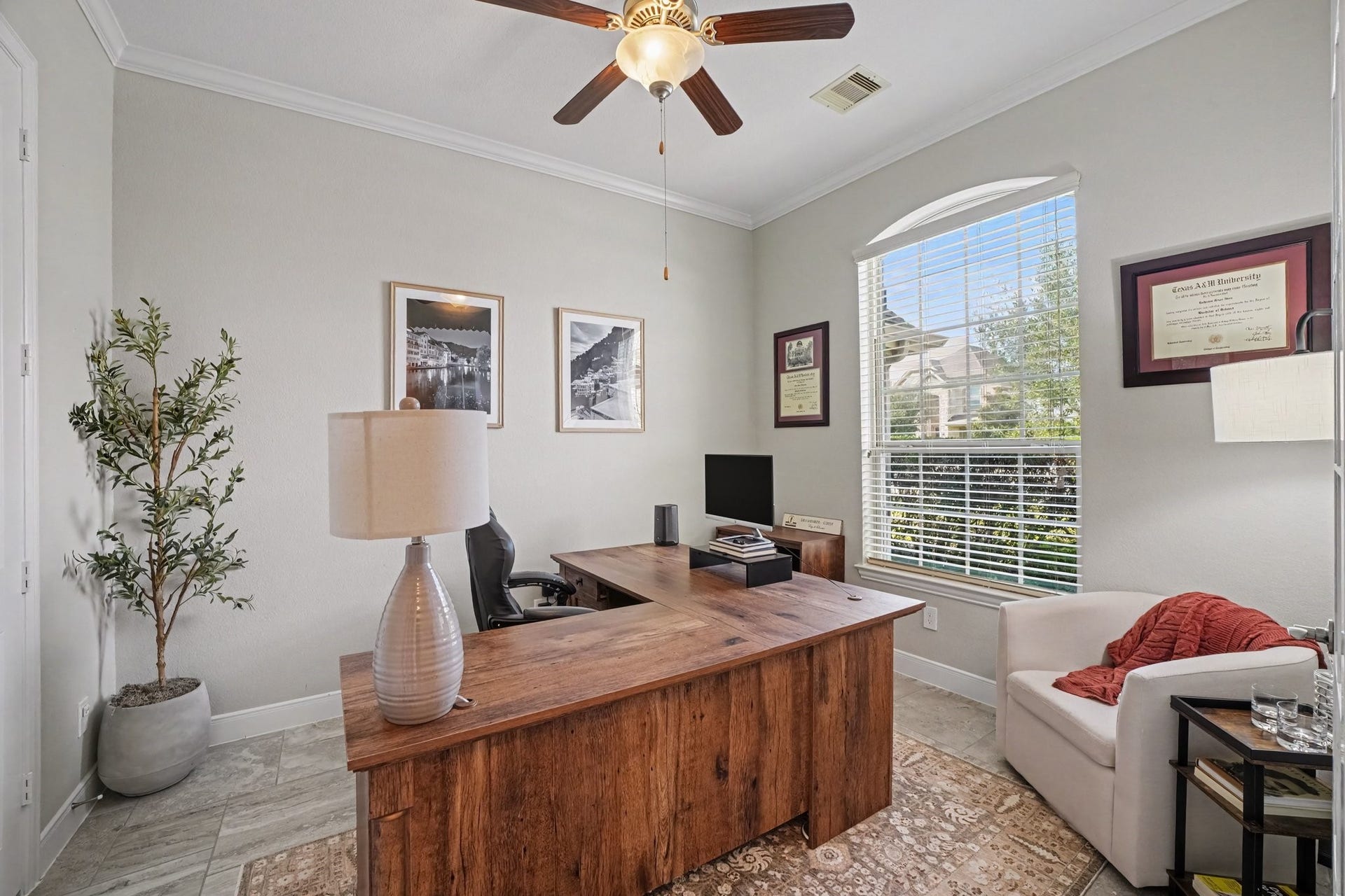 26438 Morgan Creek Lane, Katy, TX 77494 This dedicated home office offers an exceptional space for remote work, study, or management. High ceilings with crisp crown molding, a stylish wooden ceiling fan with integrated lighting, continuous tile flooring, and a decorative potted olive tree bring polish and warmth to the space.