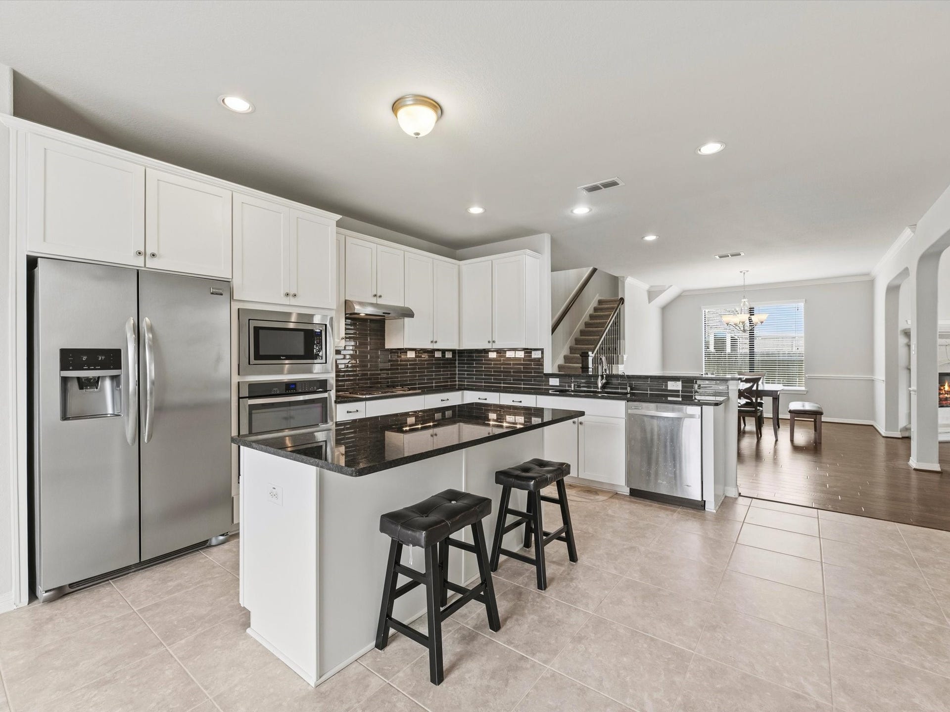 4302 Kent Ranch Court, Katy, TX 77494 the beautifully appointed kitchen opens seamlessly to the family room, creating an inviting open-concept layout. Modern finishes include a stylish subway tile backsplash, stainless steel appliances, white cabinetry, and generous counter space.