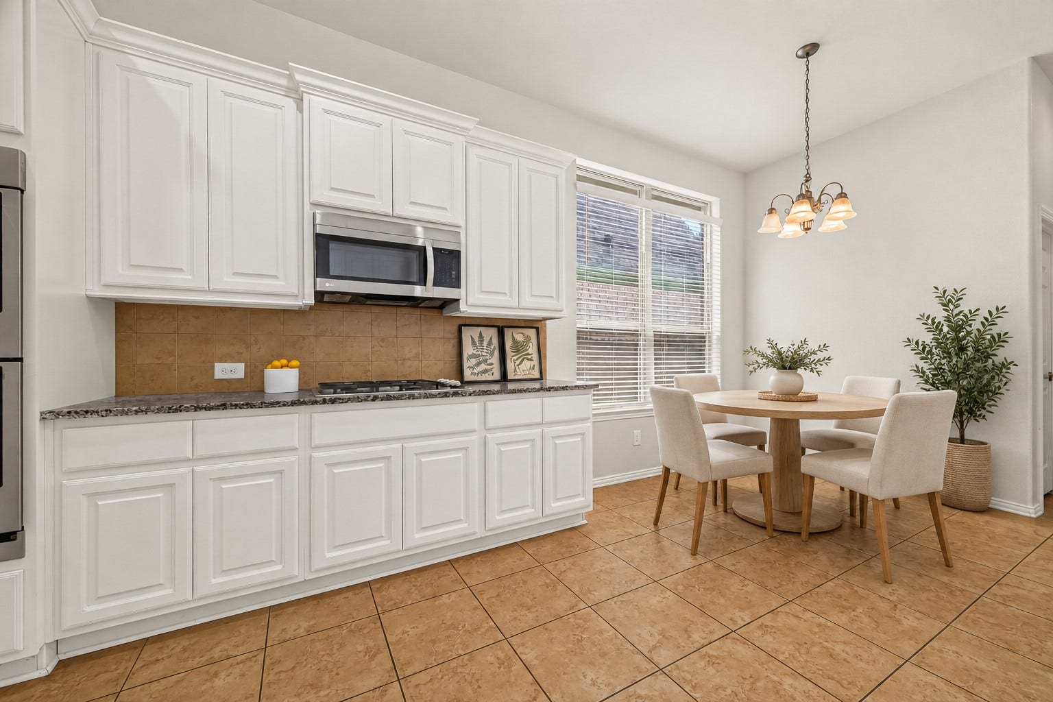 8155 Laughing Falcon Trail, Conroe, TX 77385 Bright kitchen and adjoining breakfast area with white cabinetry, abundant windows, tile flooring, and pendant lighting. Virtually Staged