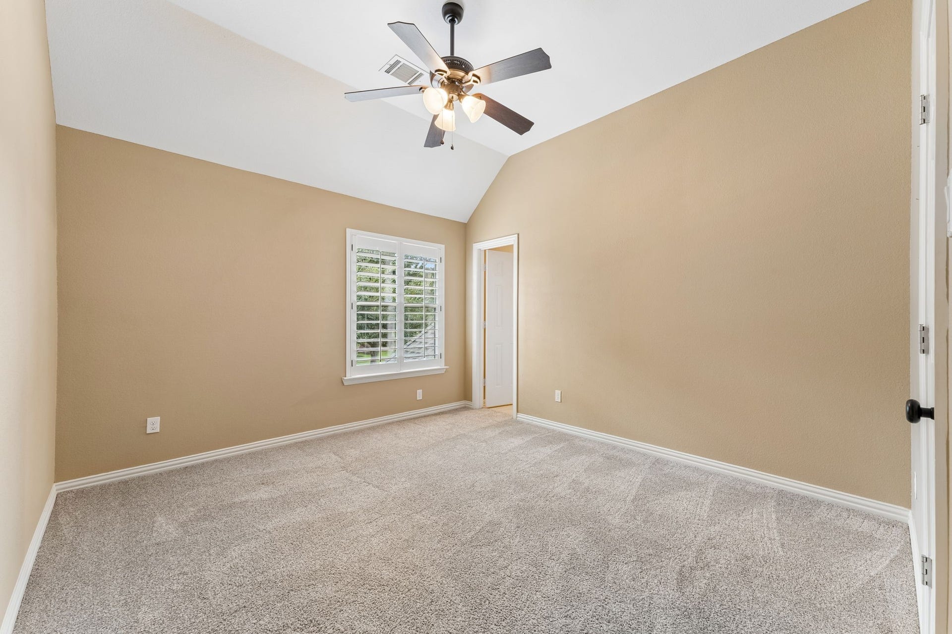 8210 Thunder Ridge Way, Missouri City, TX 77459 Bright and spacious secondary bedroom with plush carpeting, a vaulted ceiling, and a large window for natural light.
